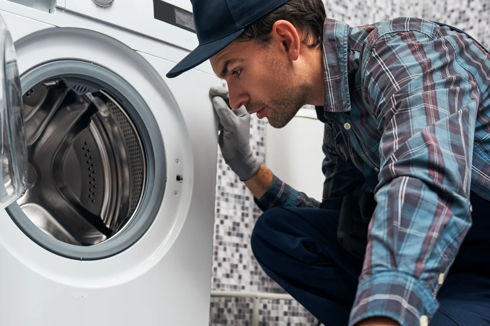 appliance-repair-north-phoenix-washer-diagnosis Appliance repair in North Phoenix — a technician kneeling to inspect the drum of a front-load washing machine for hard-water buildup.