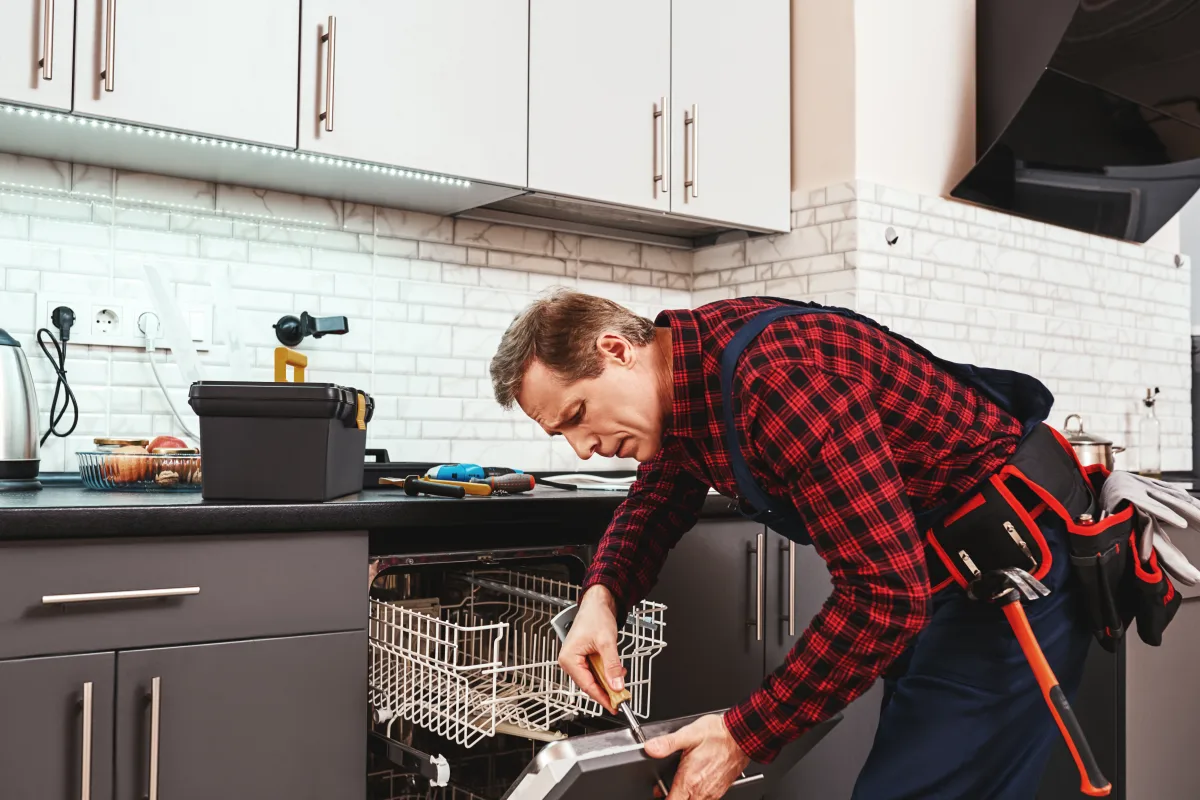 asko-dishwasher-repair-phoenix-technician-repairing-built-in-dishwasher Asko dishwasher repair in Phoenix, Arizona — a technician removing the lower rack to reach a dishwasher that will not drain.
