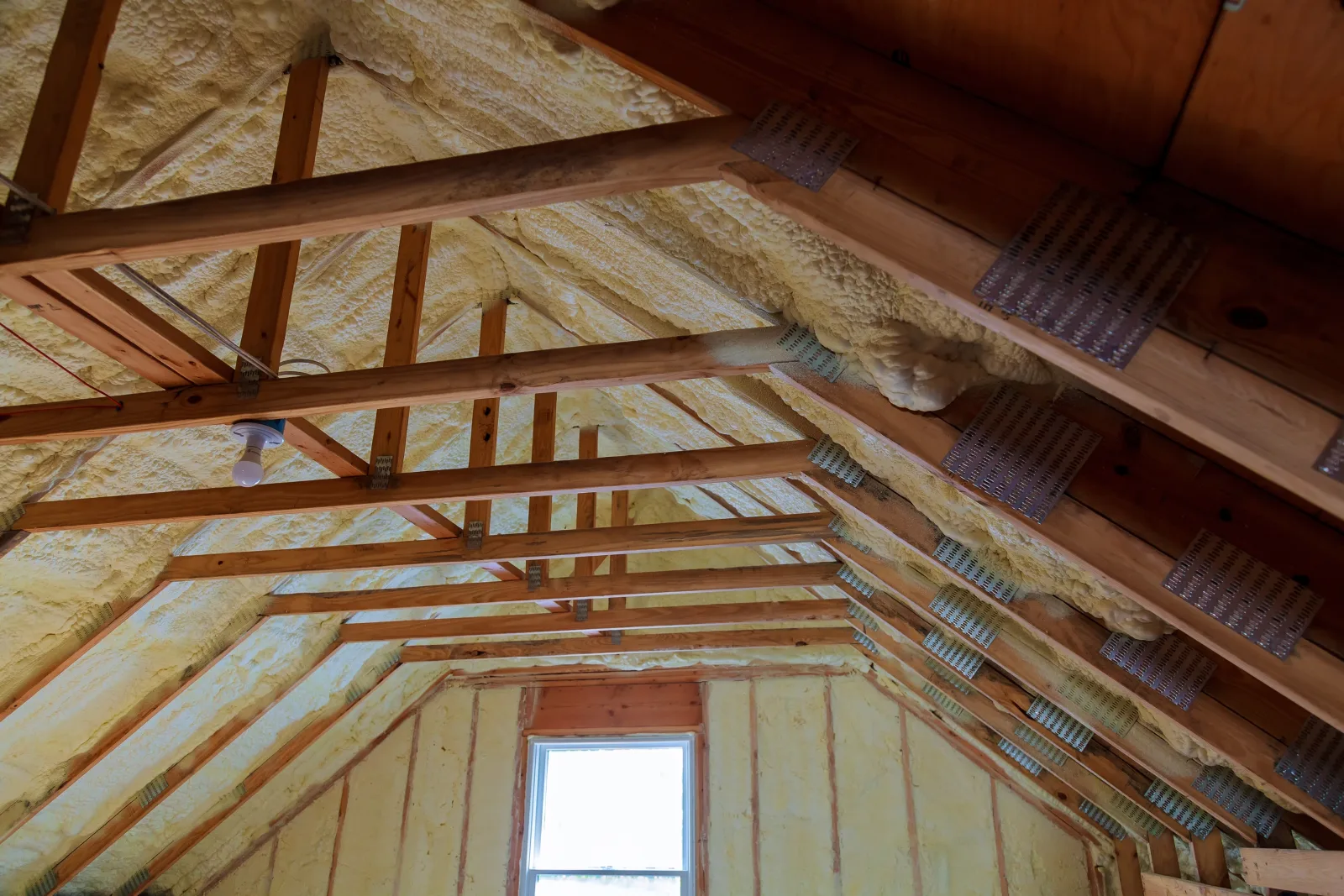 attic-insulation-phoenix-desert-conditions A bright, newly insulated Phoenix attic with open wood rafters and reflective insulation lining the roof deck, showing the kind of sun-exposed space that traps intense summer heat.