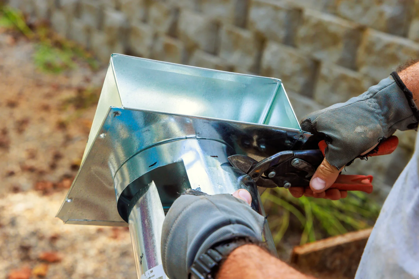 A pro fitting a metal vent hood during an attic ventilation installation at a Phoenix home.
