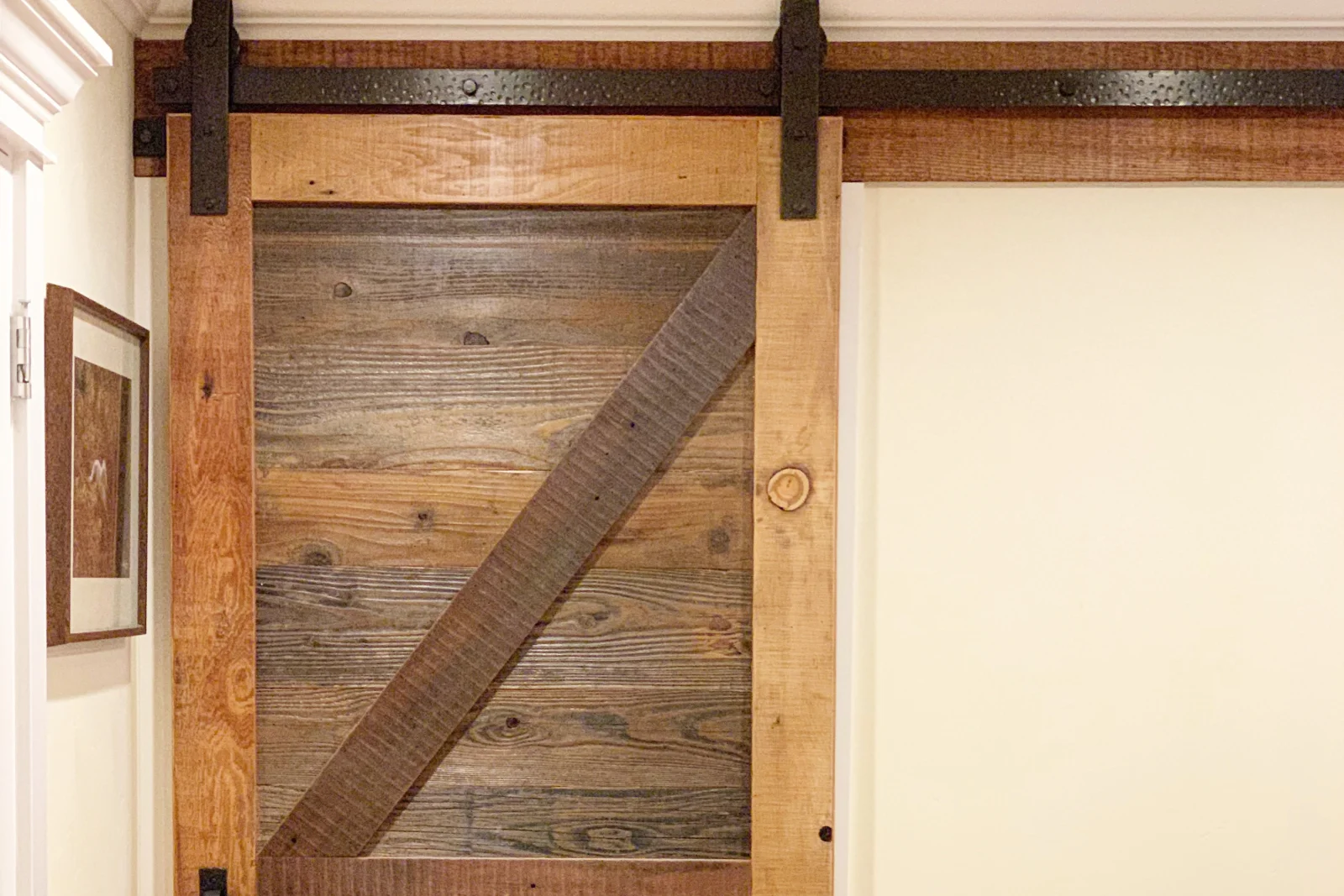 A finished sliding barn door on a Phoenix pantry with matte-black track hardware and a floor guide, the kind of clean, space-saving install a carpentry pro sizes to overlap the opening.