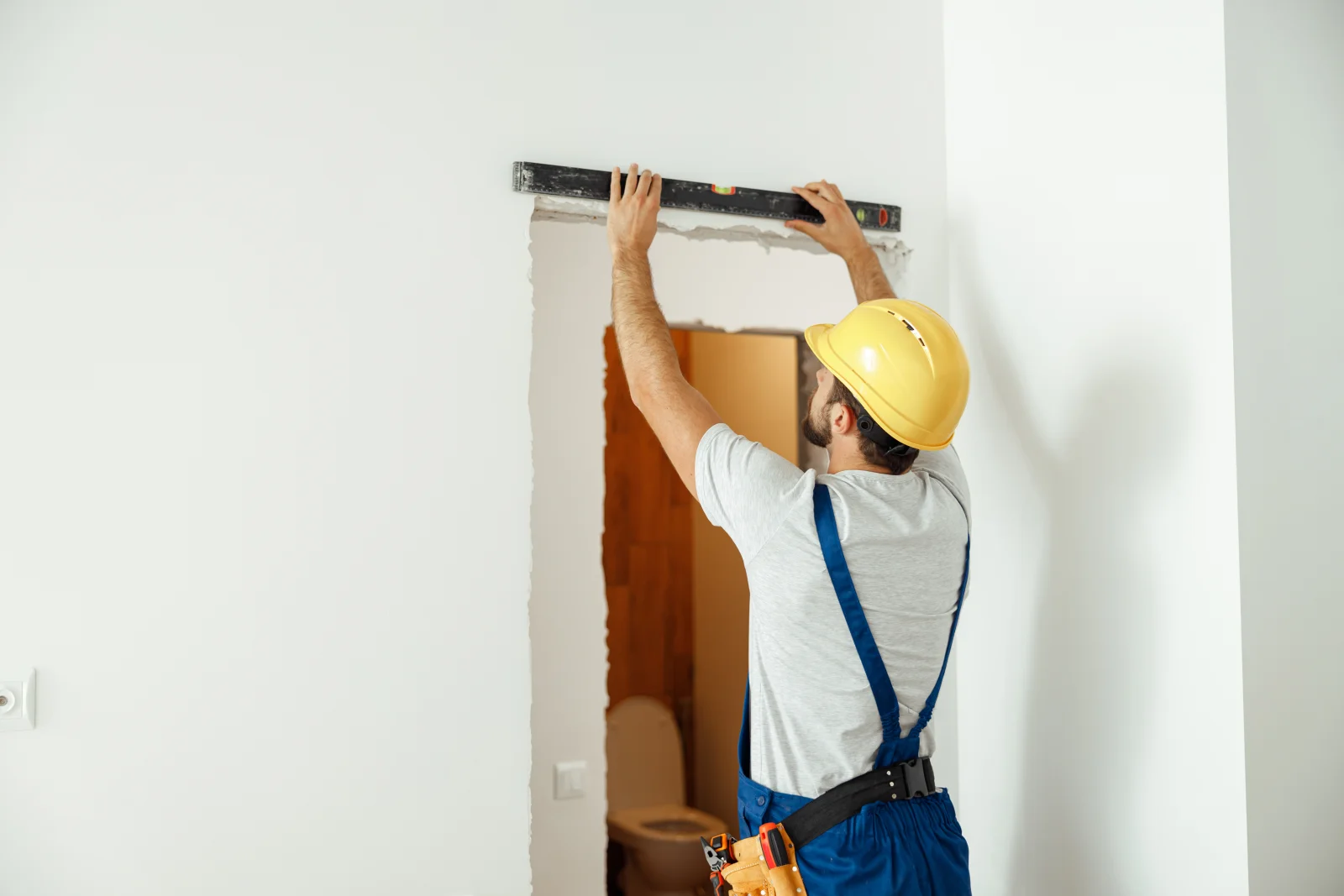 An installer lagging a barn door header board into wall studs above a Phoenix pantry opening, showing the solid backing and level track mounting that keep a sliding door safe and quiet.