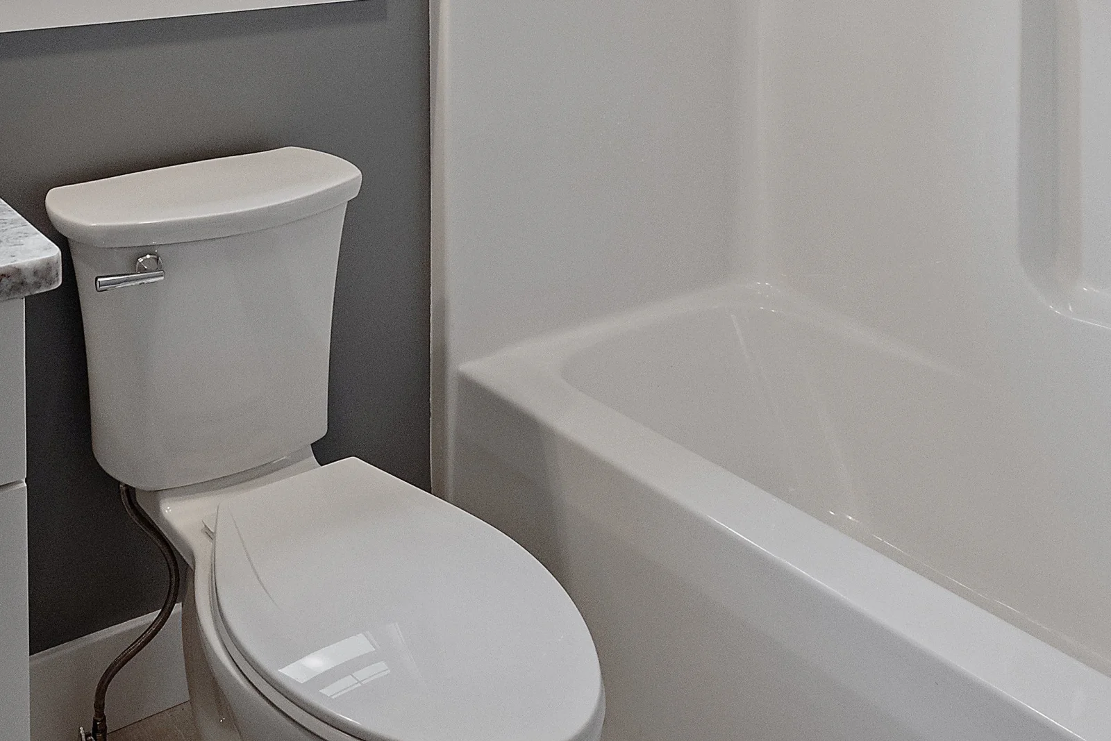 bathroom-painting-phoenix-finished-bathroom A freshly painted gray bathroom wall behind the toilet and tub, the kind of clean, moisture-resistant finish a professional bathroom painting job delivers in a Phoenix home.