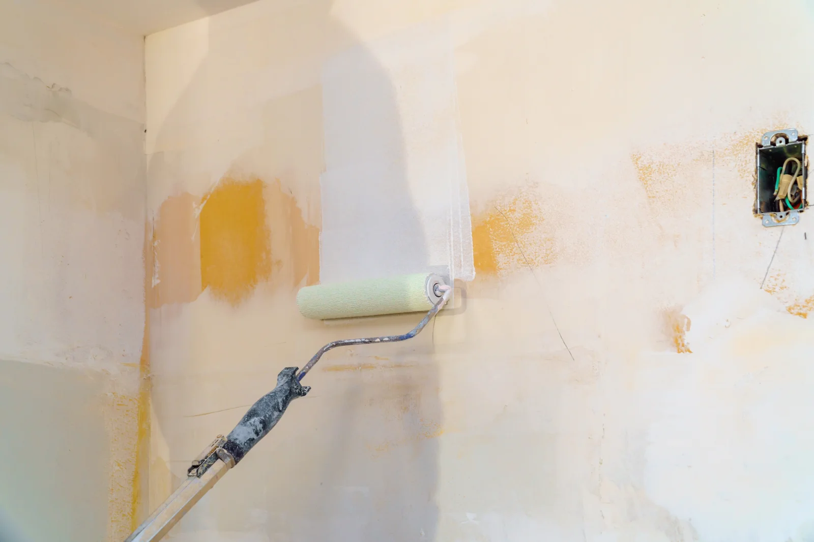 bathroom-painting-phoenix-prep-precision A paint roller priming a patched bathroom wall around an outlet box, the kind of careful prep work that keeps a Phoenix bathroom paint job from failing early.