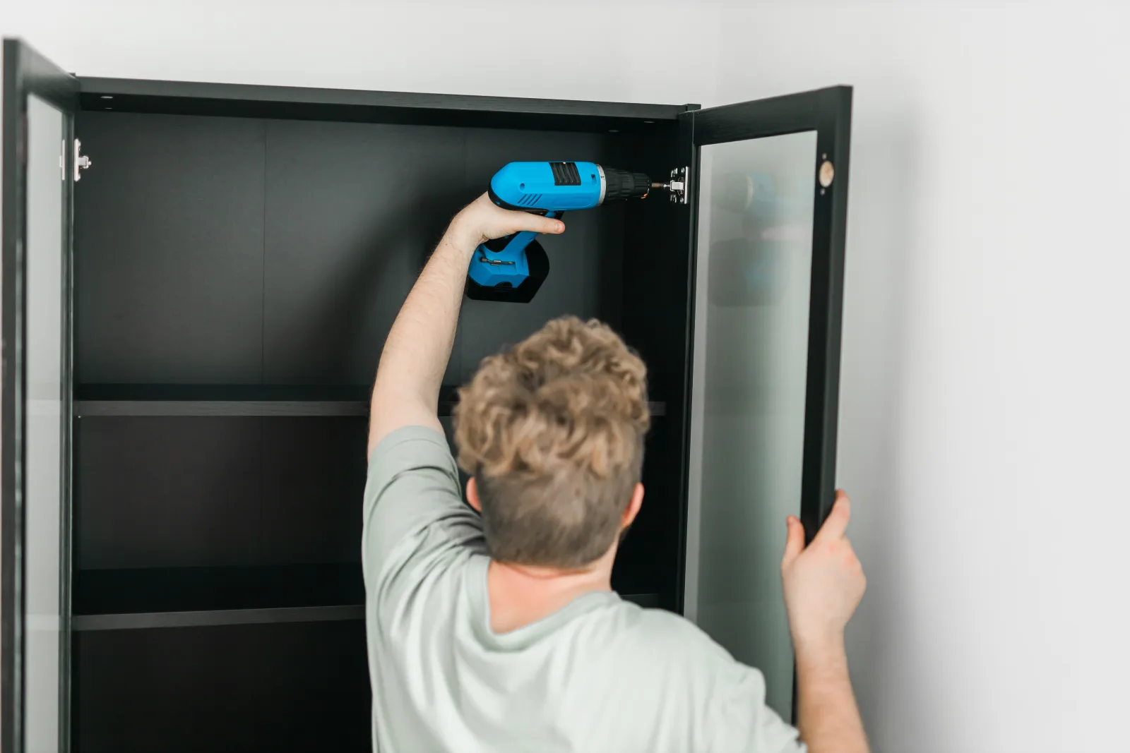 cabinet-lock-installation-phoenix-drilling-and-mounting Cabinet lock installation in Phoenix, Arizona — a technician drilling and mounting a cam lock into a cabinet interior.