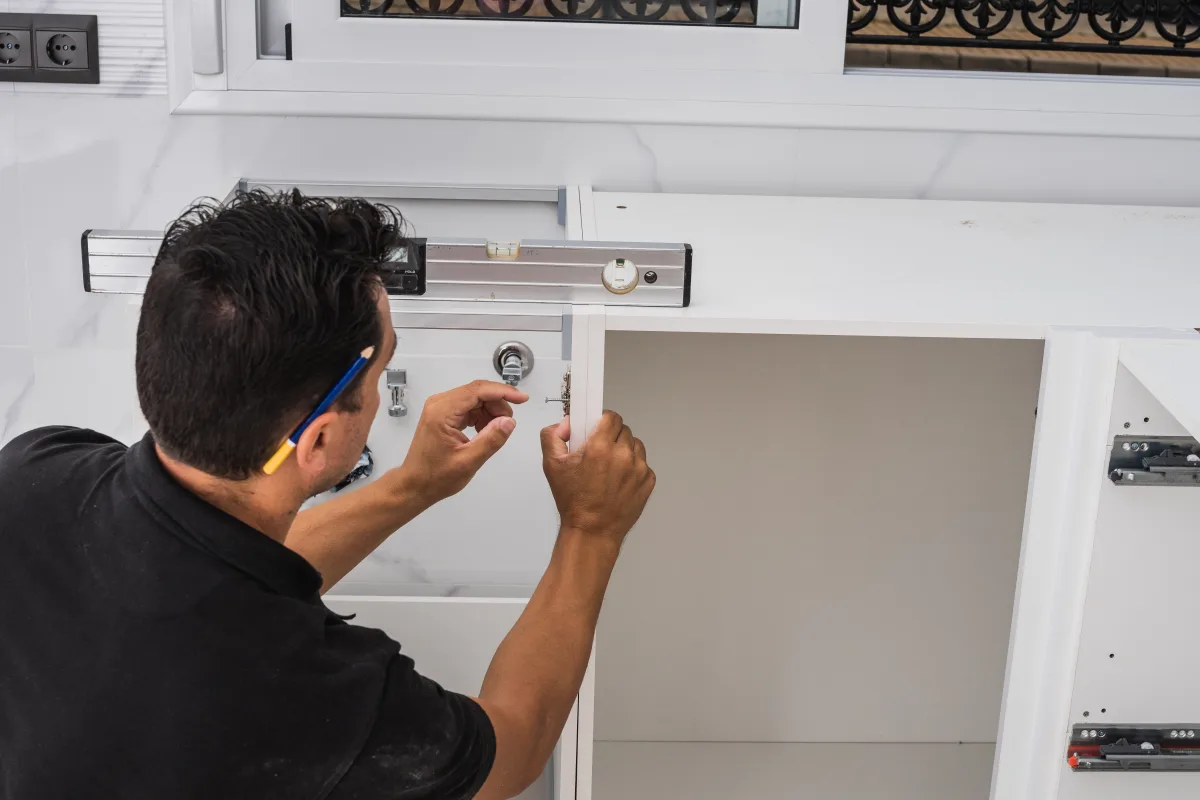 cabinet-lock-installation-phoenix-locksmith-mounting-cam-lock Cabinet lock installation in Phoenix, Arizona — a locksmith mounting a keyed cam lock into a kitchen cabinet door.