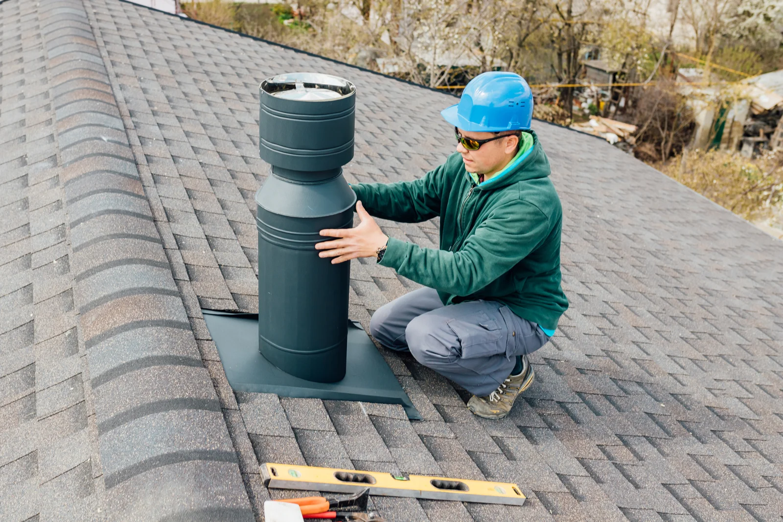 Chimney repair in Phoenix, Arizona — a technician in a hard hat installing a new chimney cap on a rooftop.