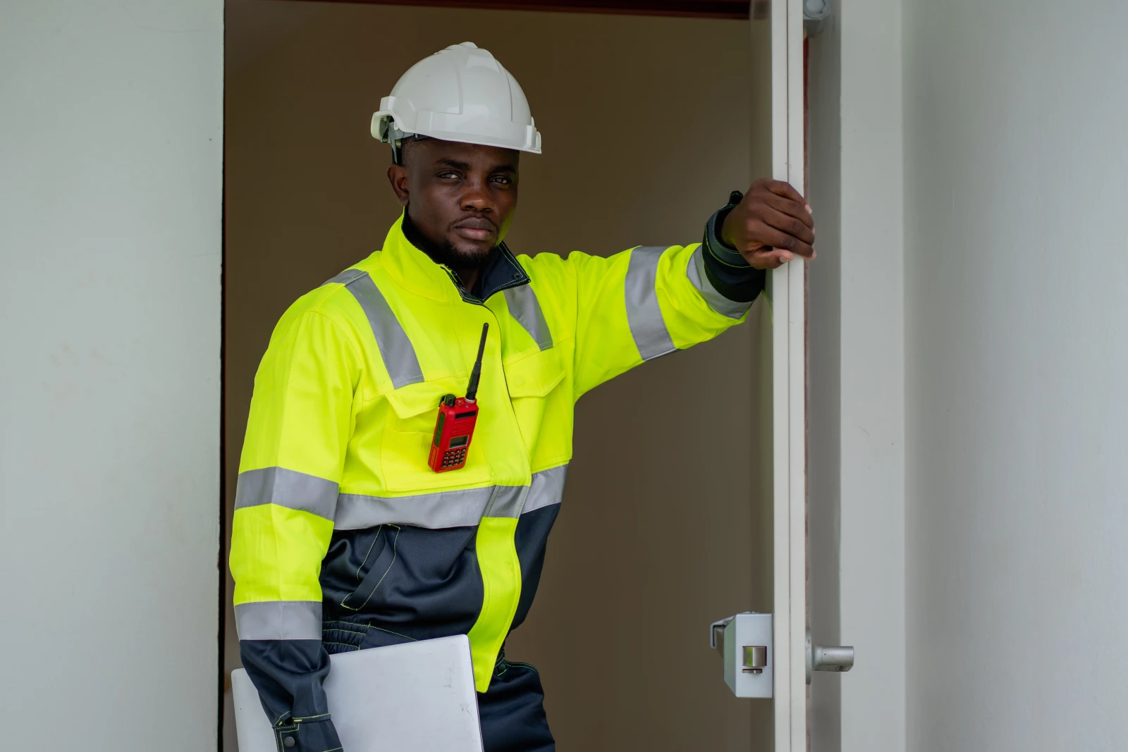 commercial-locksmith-phoenix-door-hardware-inspection A commercial locksmith in high-visibility gear inspecting deadbolt door hardware at a Phoenix business.