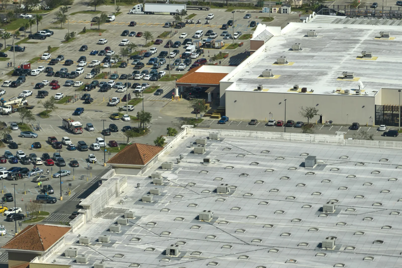 commercial-roof-replacement-phoenix-rooftop-aerial Aerial view of a large commercial flat roof with rooftop HVAC units above a busy Phoenix-area shopping center parking lot, showing the scale of a typical commercial roof replacement project.
