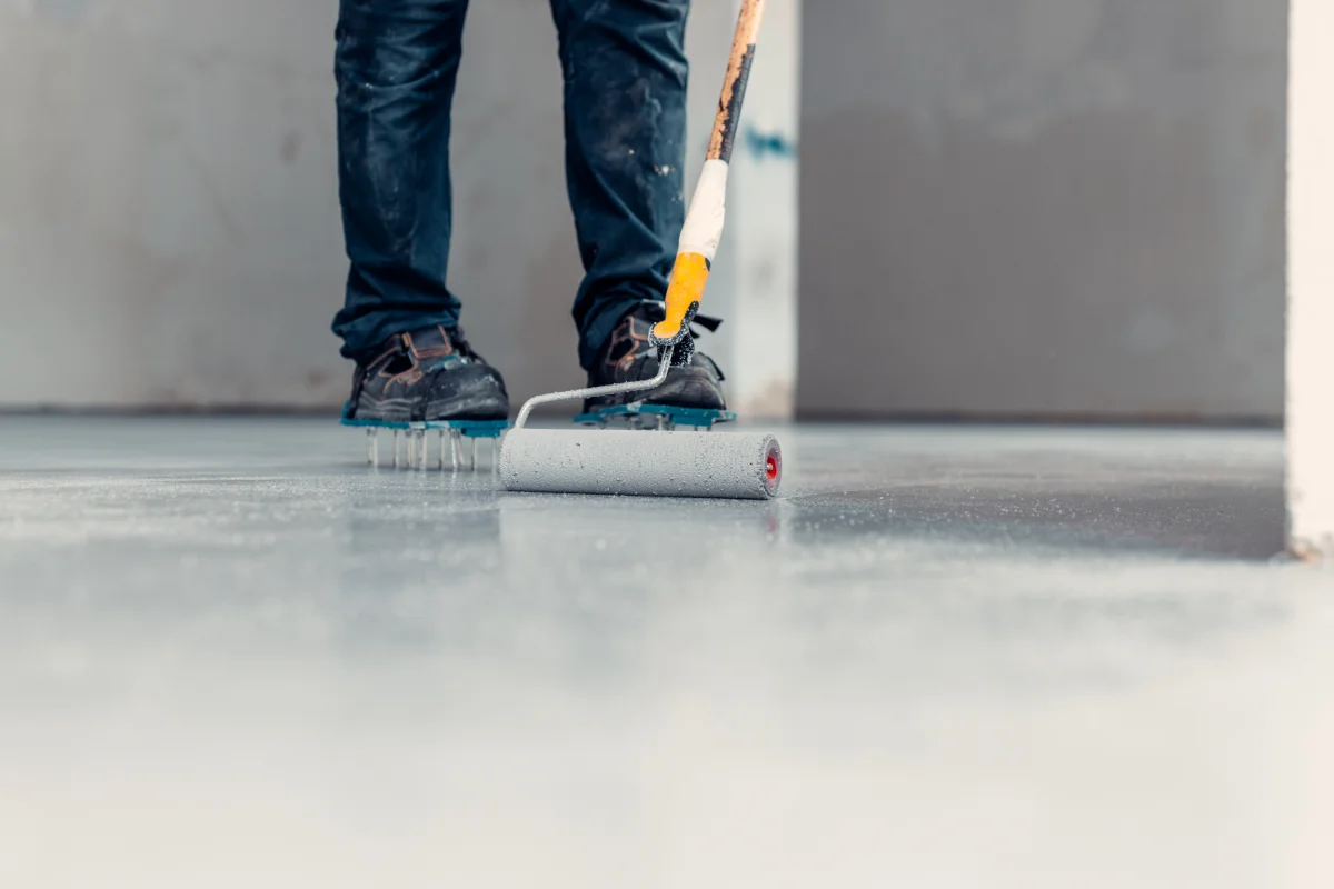 concrete-coating-phoenix-pro-applying-protective-coating Concrete coating in Phoenix, Arizona — a pro rolling a protective coating onto a garage floor.