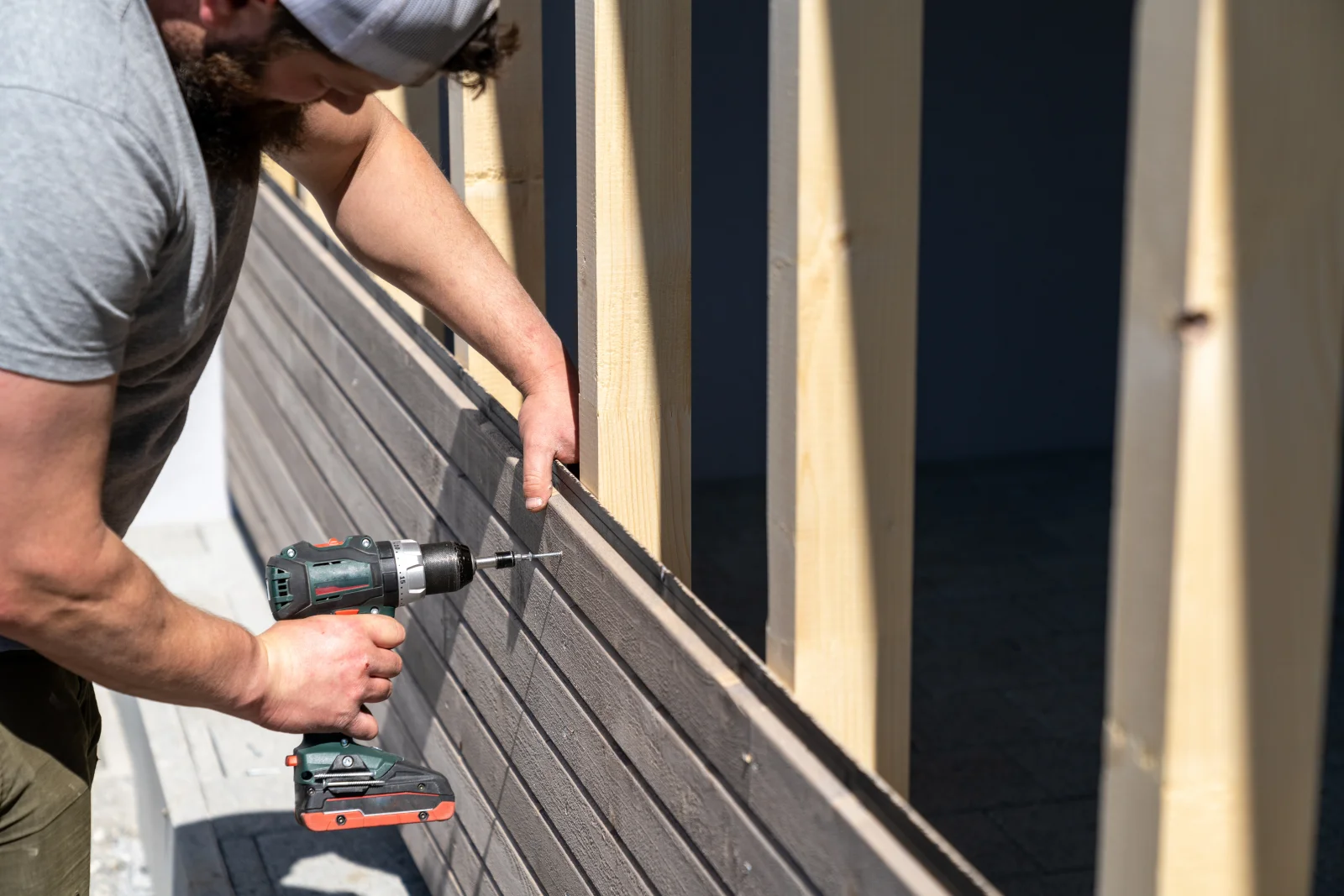 A deck builder installing heat-resistant composite decking boards in direct Phoenix sun.