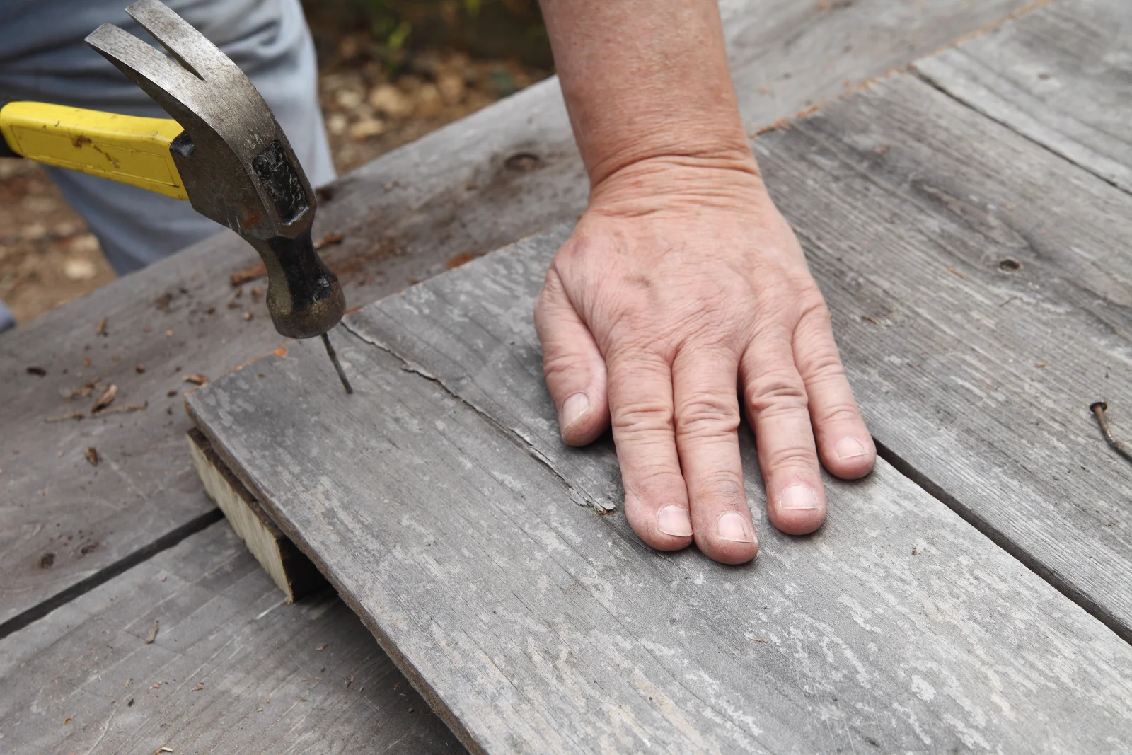 A close-up of a contractor hand-fastening deck boards during a Phoenix, Arizona deck installation.
