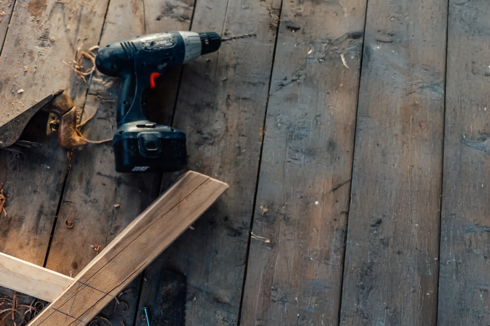 A weathered Phoenix deck board being removed and replaced with a drill and matching new board.