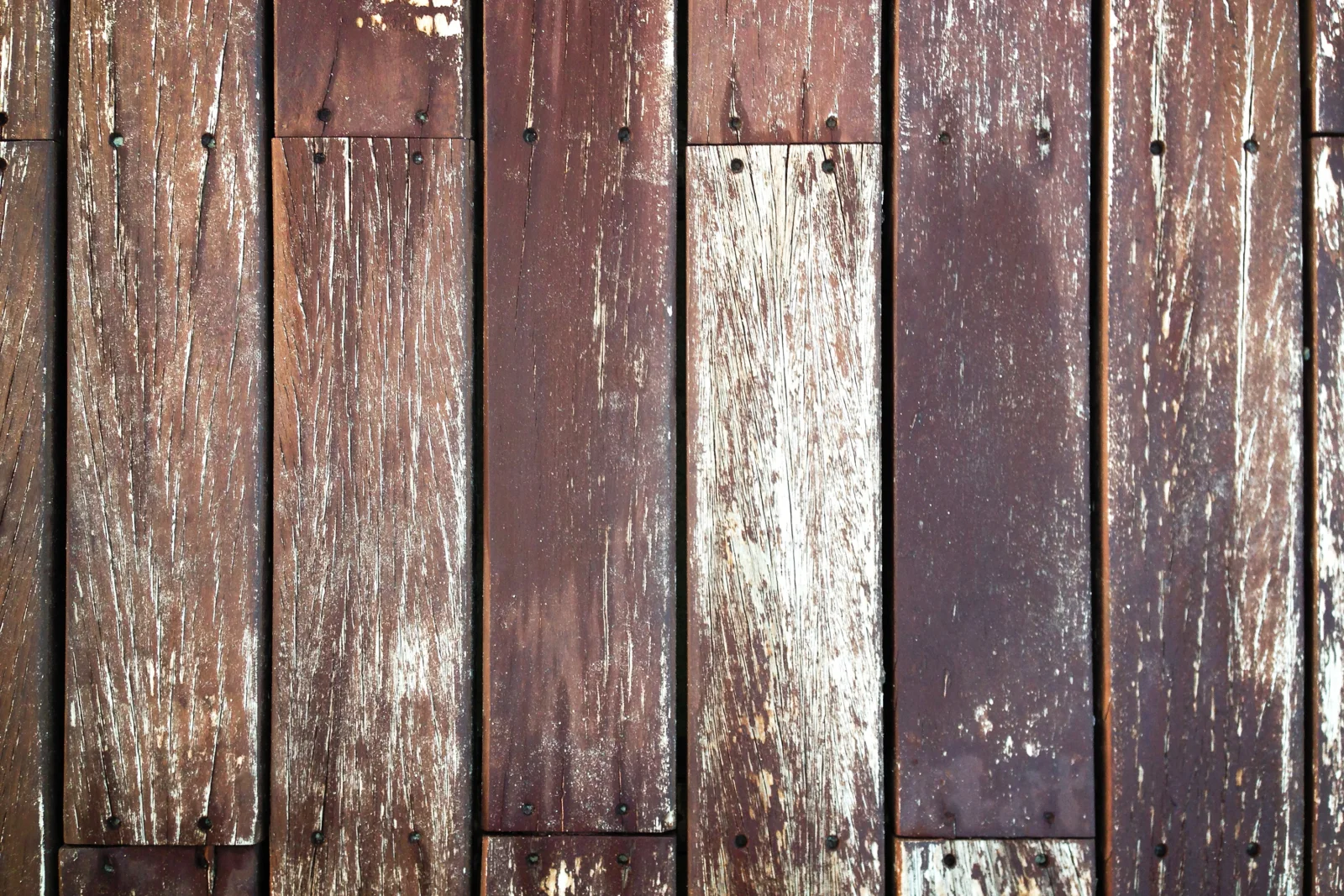 Close-up of sun-bleached, cracked wood deck boards showing the surface checking common on Phoenix decks.