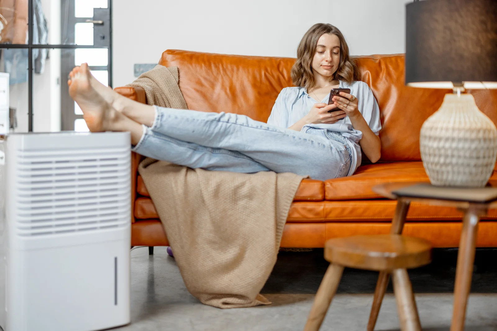 Dehumidifier installation in Phoenix, Arizona — a homeowner relaxing comfortably on a couch after balanced indoor humidity is restored.