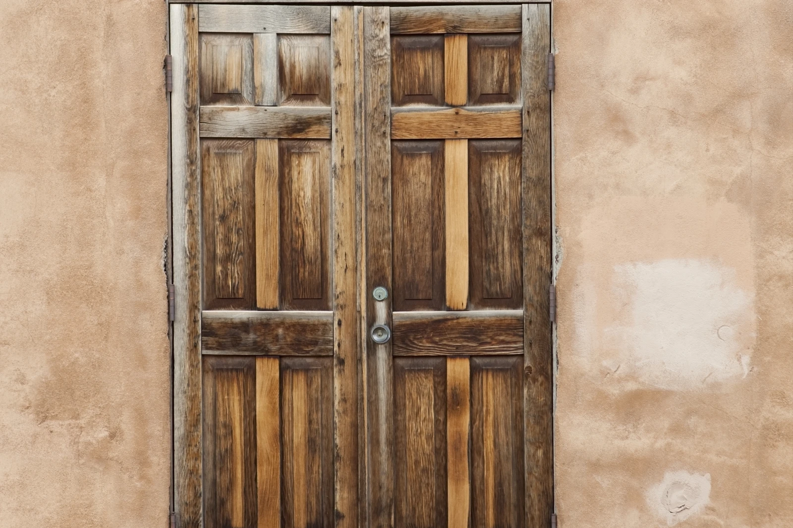 door-installation-phoenix-desert-entry A sun-faded, warped wood front door on a Phoenix desert home in harsh afternoon light, showing the UV damage and heat stress that make desert doors fail and need replacement.