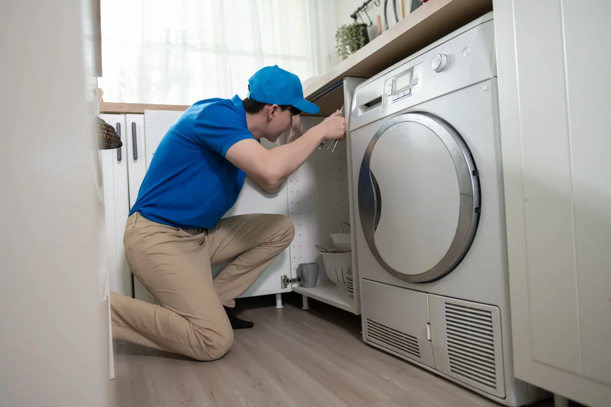 dryer-repair-phoenix-appliance-technician Dryer repair in Phoenix, Arizona — a technician in a collared work shirt diagnosing a laundry-room dryer that will not heat.