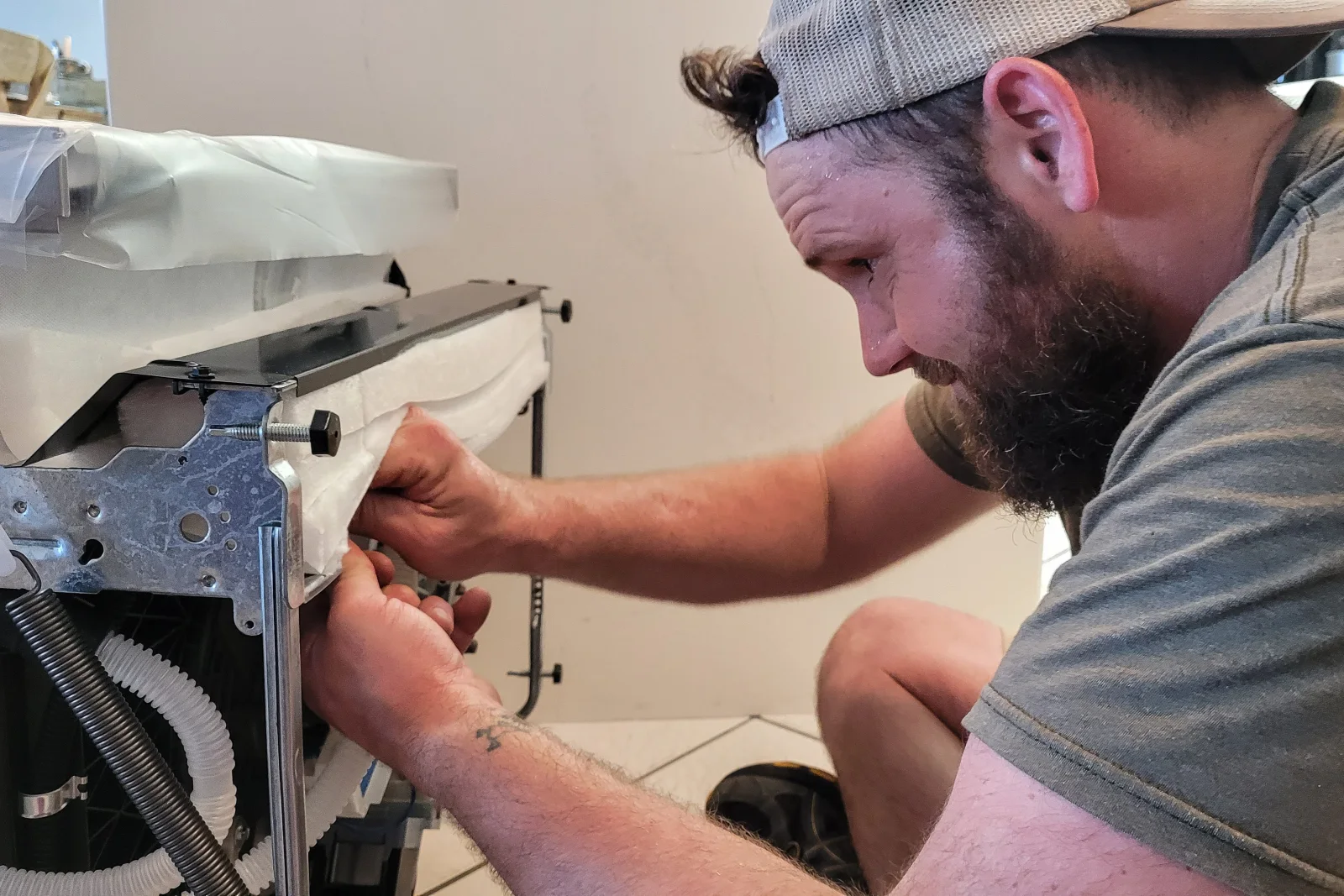 dryer-repair-phoenix-technician-diagnosing An appliance technician pulling a dryer away from a Phoenix laundry room wall to inspect the vent connection and heating element before quoting a repair.