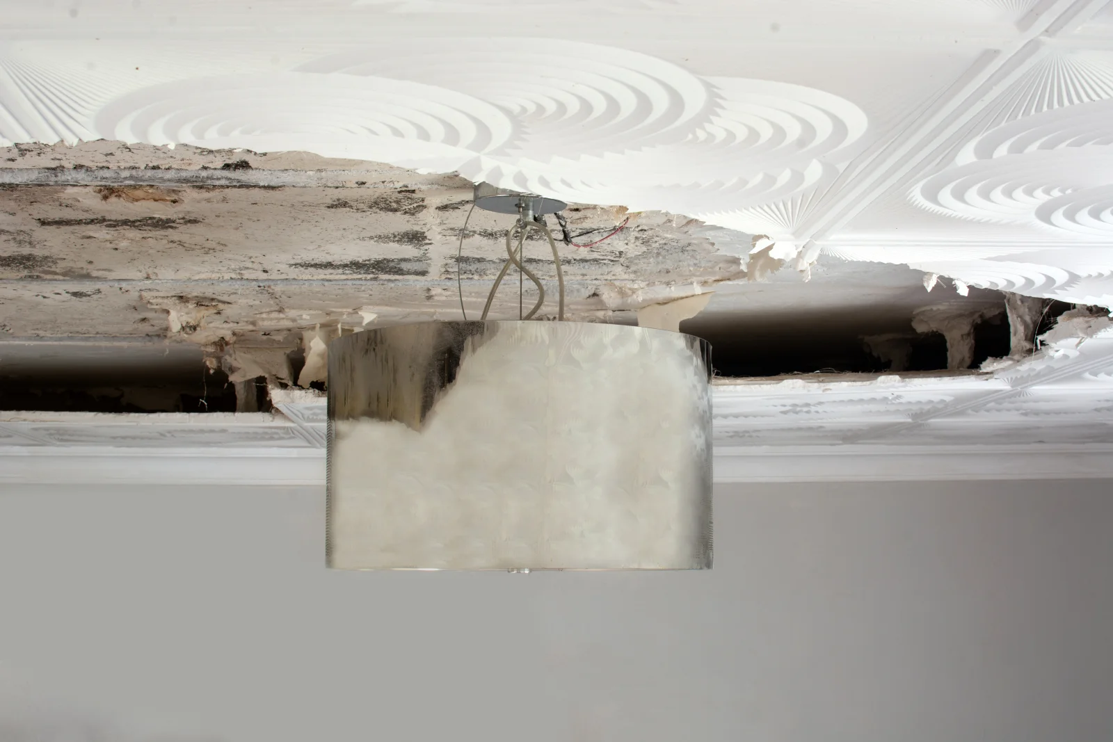 drywall-repair-phoenix-water-stain-diagnosis A contractor inspecting a water-stained ceiling panel in a Phoenix home to find the source of the leak before patching the drywall.