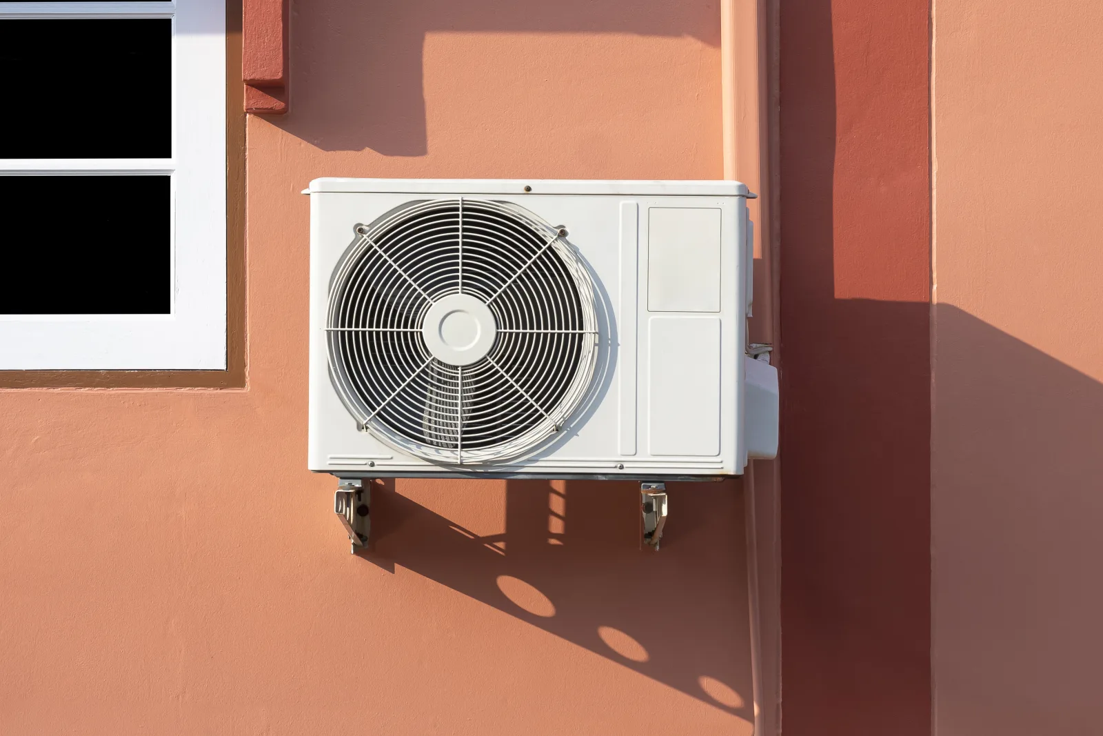 ductless-ac-replacement-phoenix-condenser-heat A new ductless mini-split condenser mounted beside a Phoenix home in harsh afternoon desert sun, showing the heat load a properly sized replacement system has to overcome.