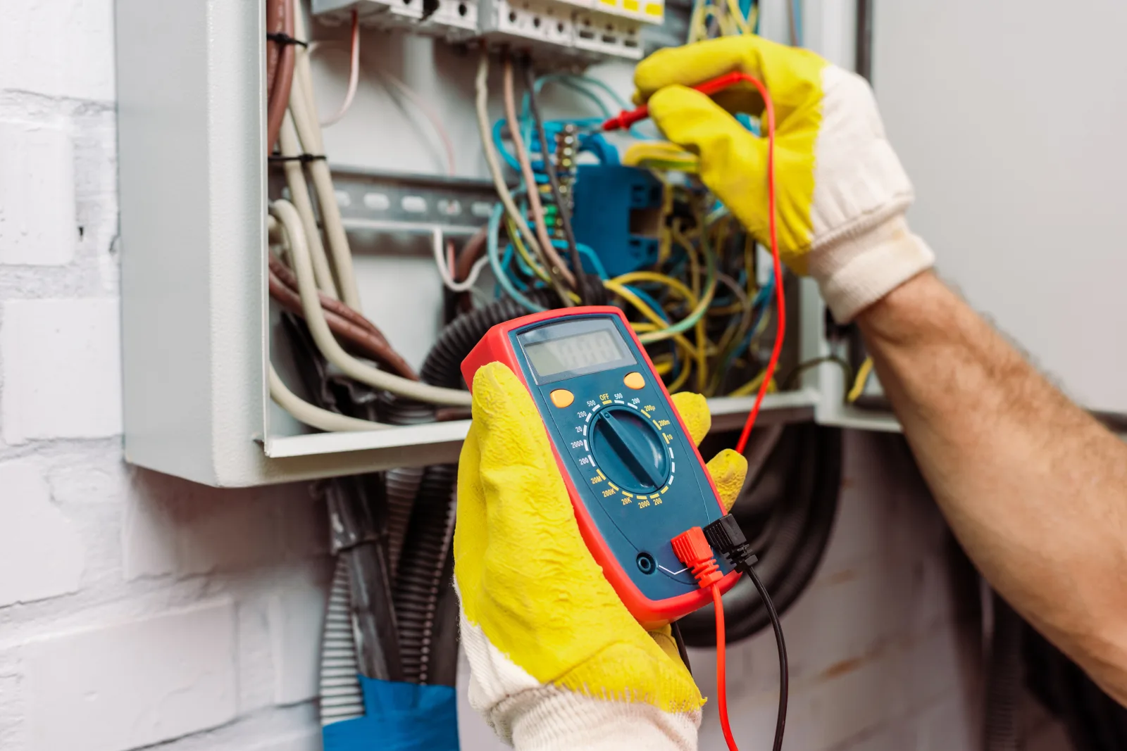 electric-service-phoenix-diagnosis A Phoenix electrician using a multimeter to diagnose a home electrical panel issue.
