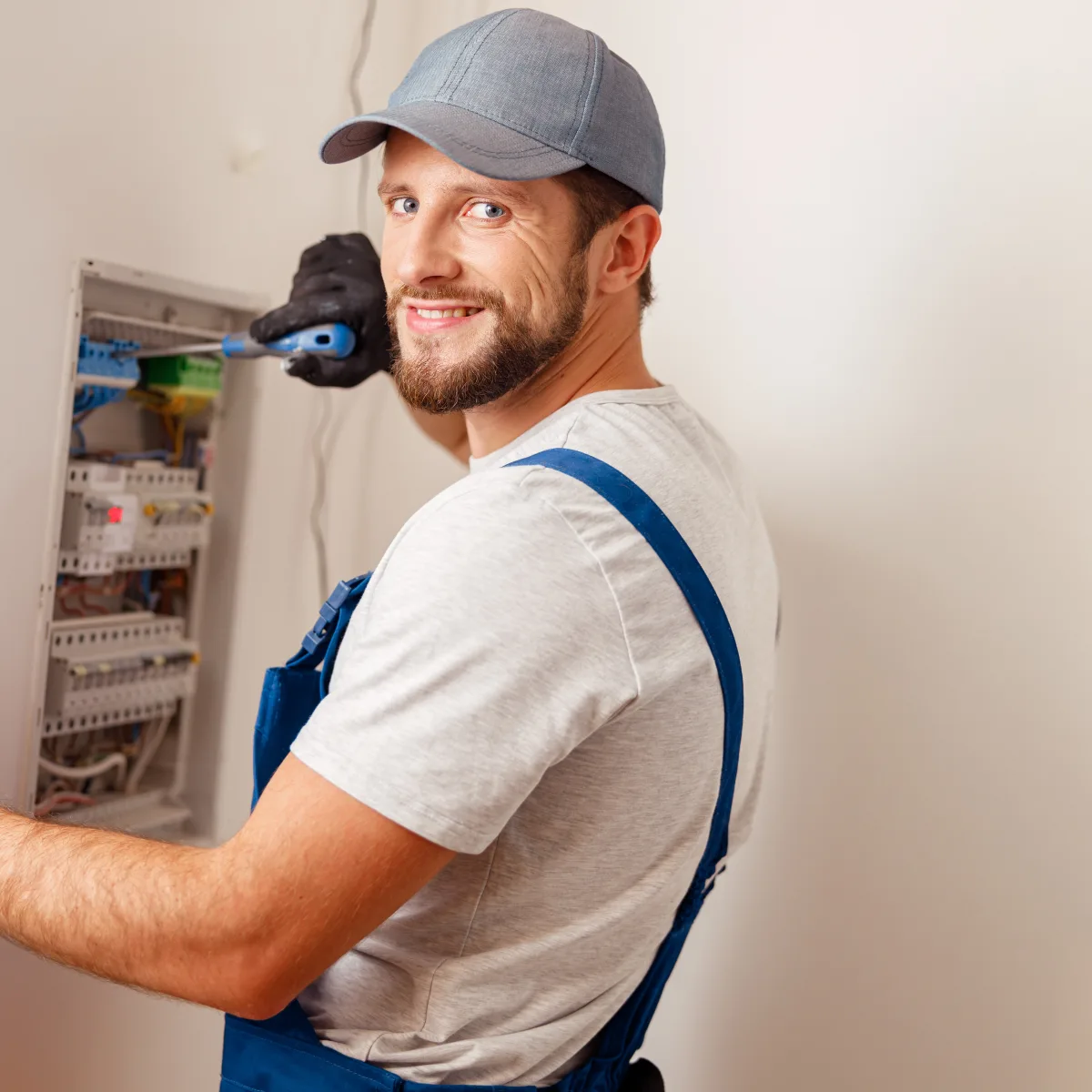 electric-service-phoenix-repair Electric service in Phoenix — a licensed electrician in a branded uniform working at a home electrical panel.