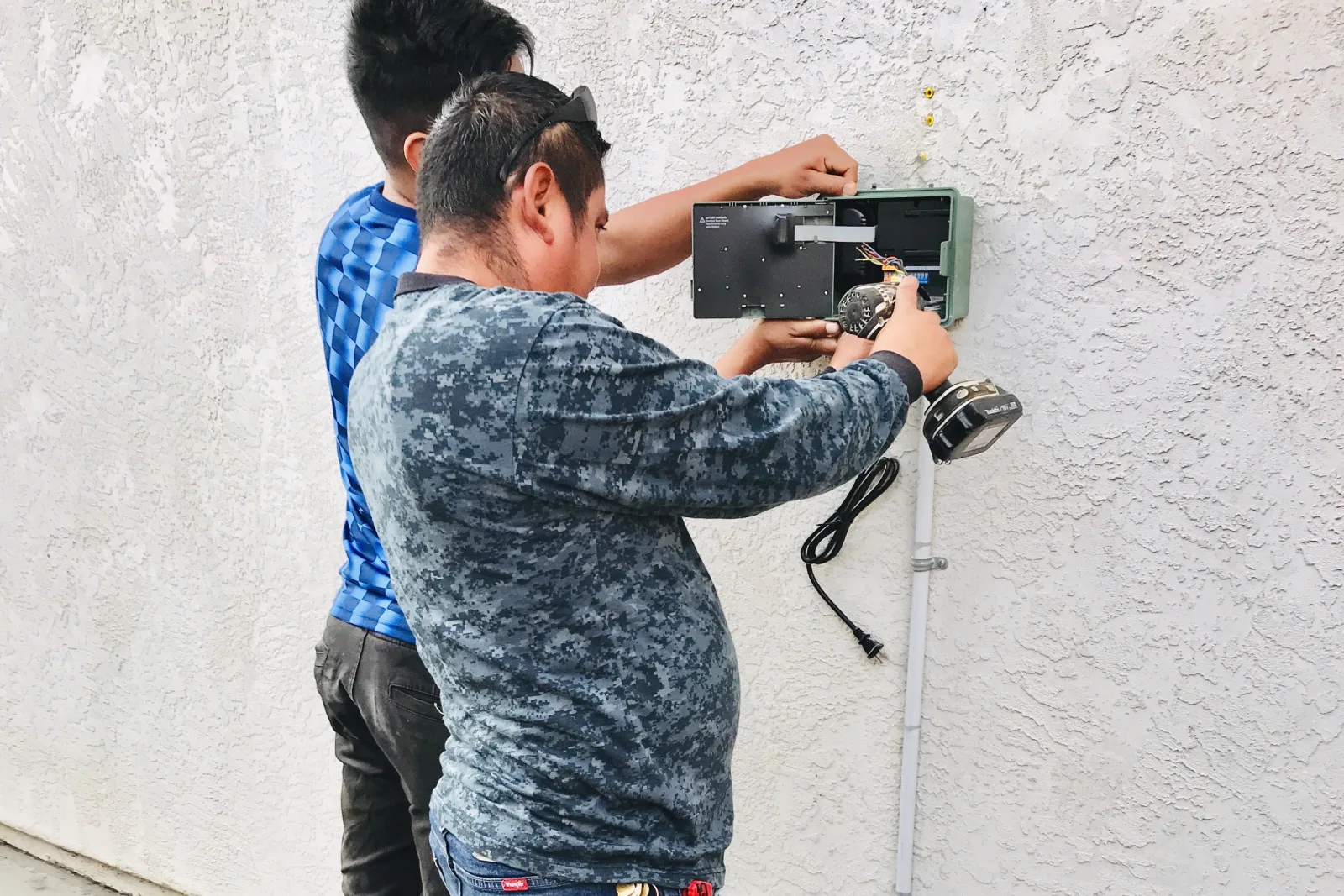 electric-service-phoenix-panel-heat A licensed electrician inspecting a home electrical panel under harsh Phoenix desert sun.