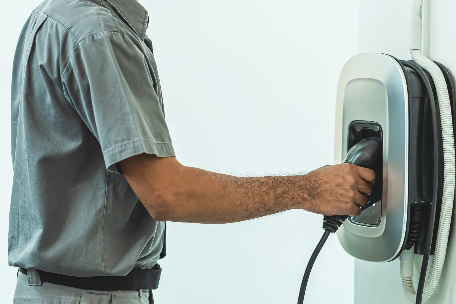 A licensed Phoenix electrical contractor connecting the charging cable on a newly installed Level 2 EV charger mounted on a home's garage wall.