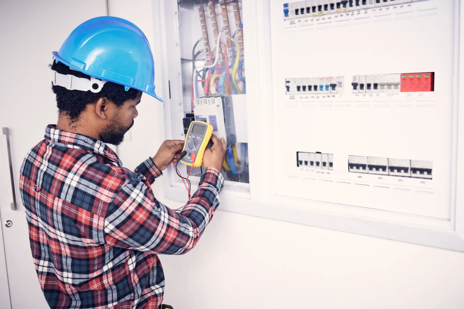 A Phoenix electrical contractor using a digital multimeter to test a home's breaker panel and verify it safely carries the electrical load.