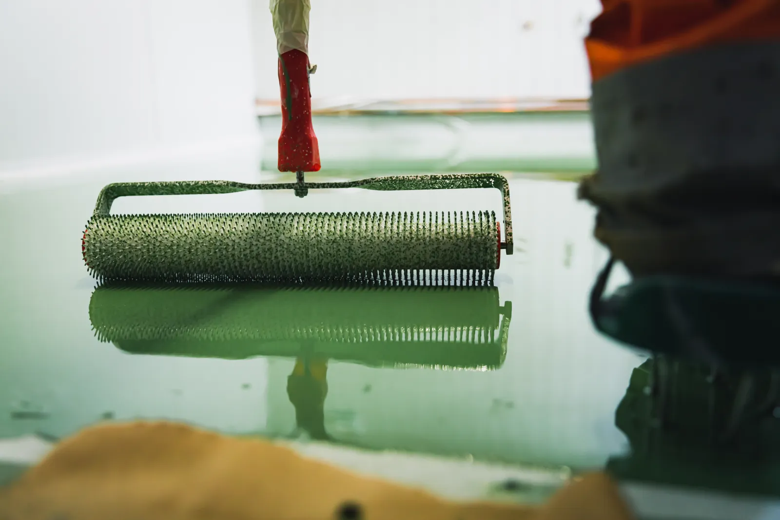 epoxy-garage-floor-phoenix-coating A professional installer rolling a fresh epoxy coating onto a diamond-ground, crack-repaired garage floor slab in a Phoenix home.