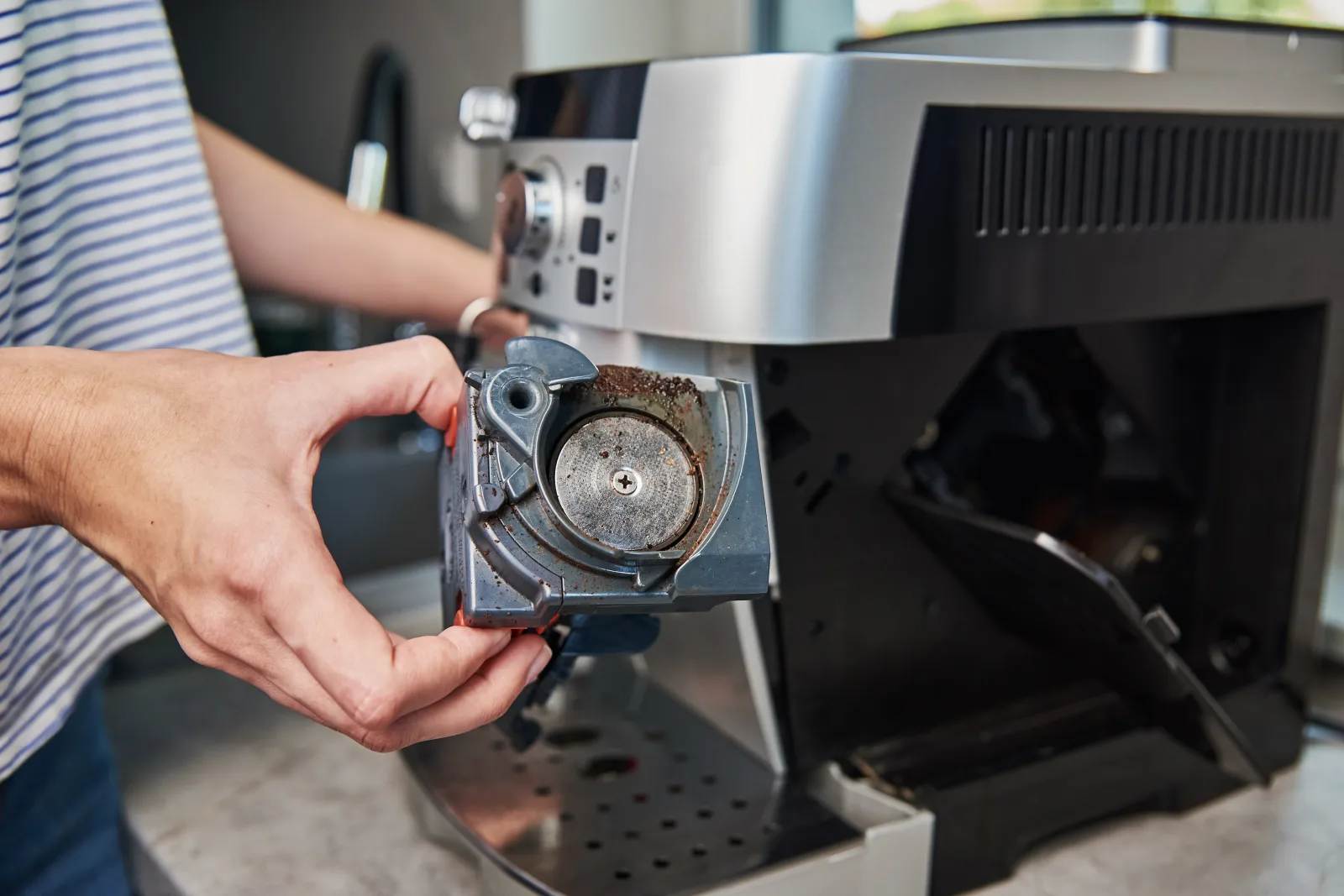 Espresso machine repair in Phoenix, Arizona — removing a scale-crusted part from an espresso machine during descaling service.