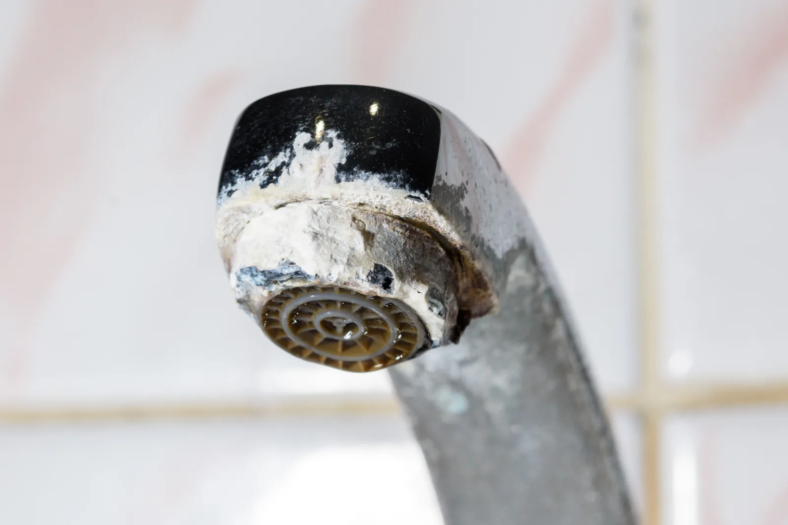 faucet-repair-phoenix-hard-water-mineral-scale Mineral scale buildup from Phoenix hard water on a faucet aerator, the kind of scale that wears out a cartridge and causes drips and low water pressure.