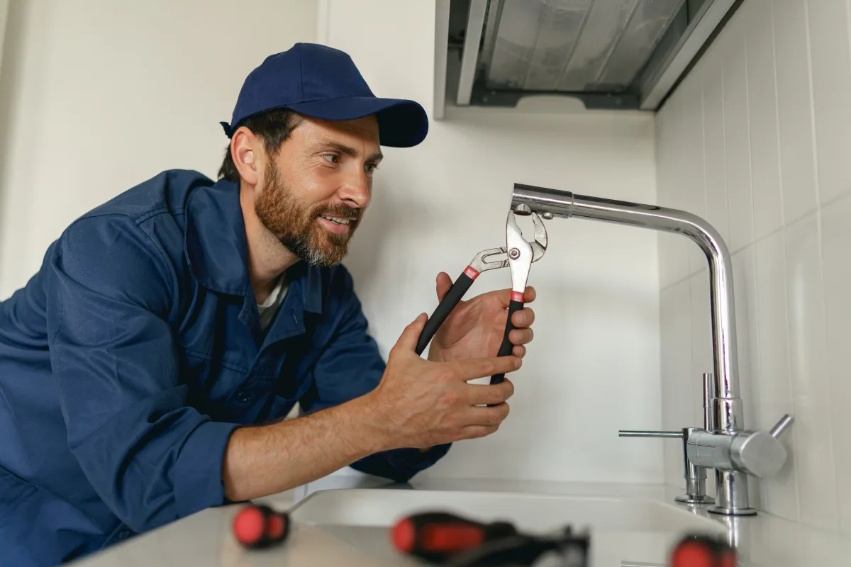 faucet-repair-phoenix-plumber Faucet repair in Phoenix, Arizona — a licensed plumber repairing a kitchen faucet with pliers.