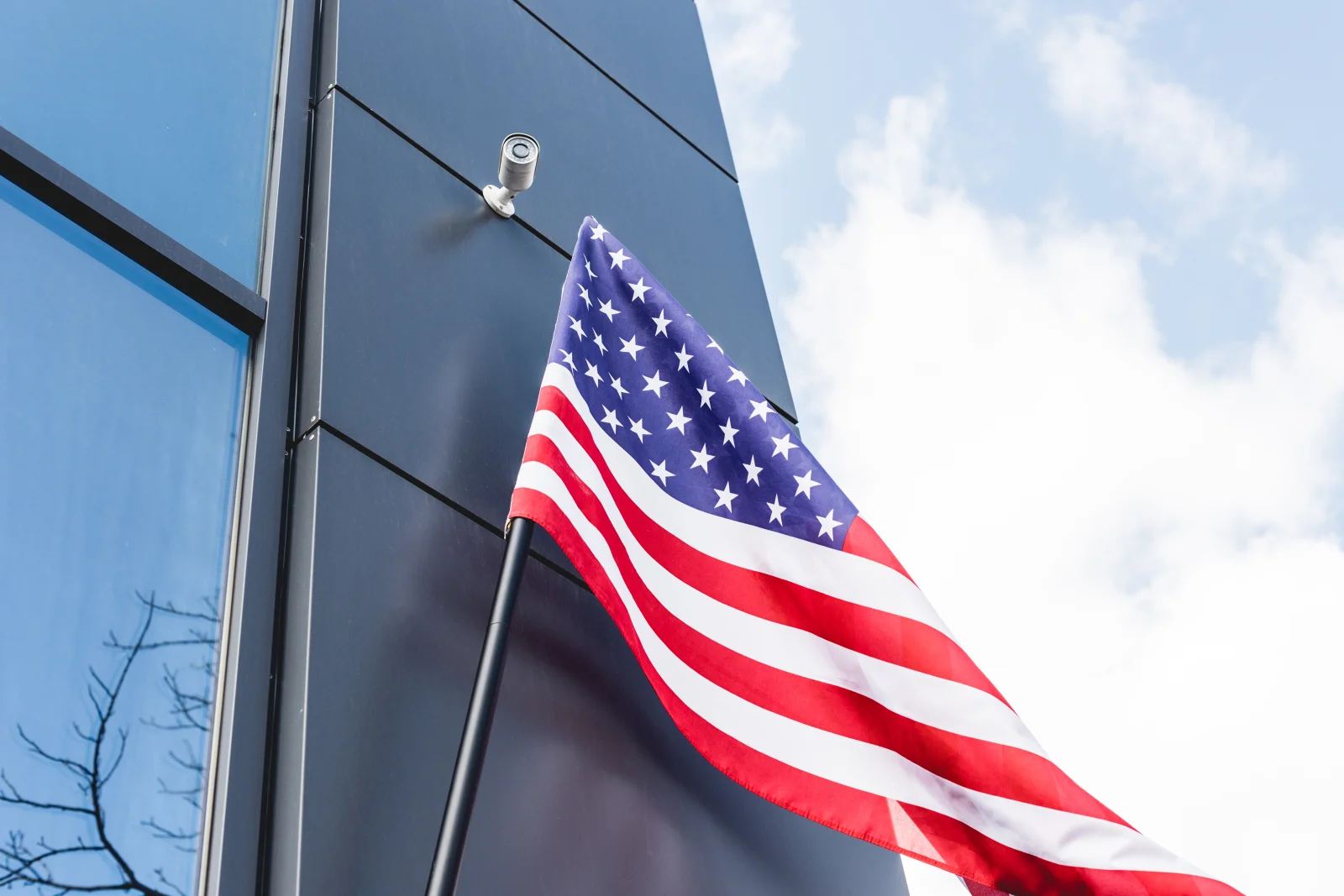 An American flag on a wall-mounted bracket pole installed on the exterior of a modern Phoenix-area commercial building.