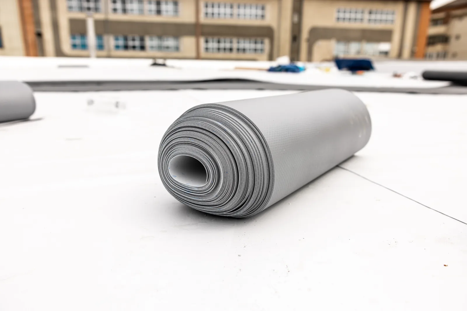 Flat roof installation in Phoenix, Arizona — a rolled gray TPO membrane sheet ready to be installed on a flat roof deck.