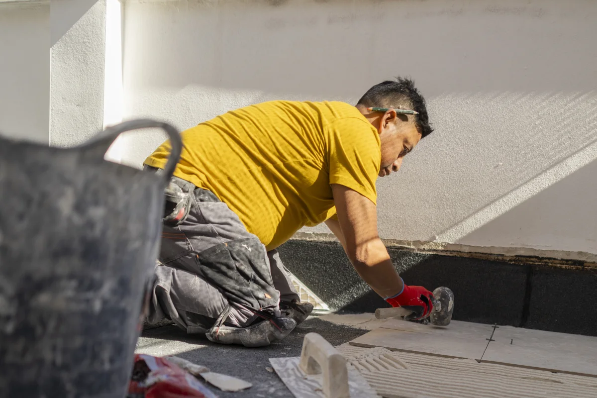 flat-roof-replacement-phoenix-new-membrane-install Flat roof replacement in Phoenix, Arizona — a roofing crew rolling out a new white TPO membrane on a residential flat roof.