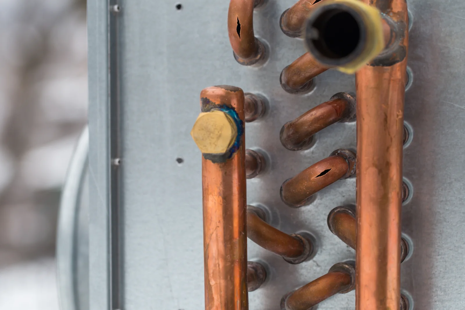 Close-up of copper refrigerant coil lines on a Phoenix air conditioning unit, the kind of hardware a freon recharge relies on.