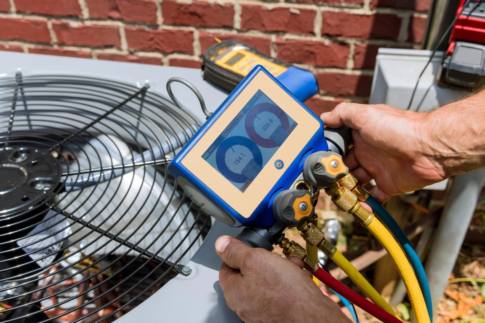 A digital manifold gauge set connected to a Phoenix home's outdoor air conditioning unit during a refrigerant diagnostic check.