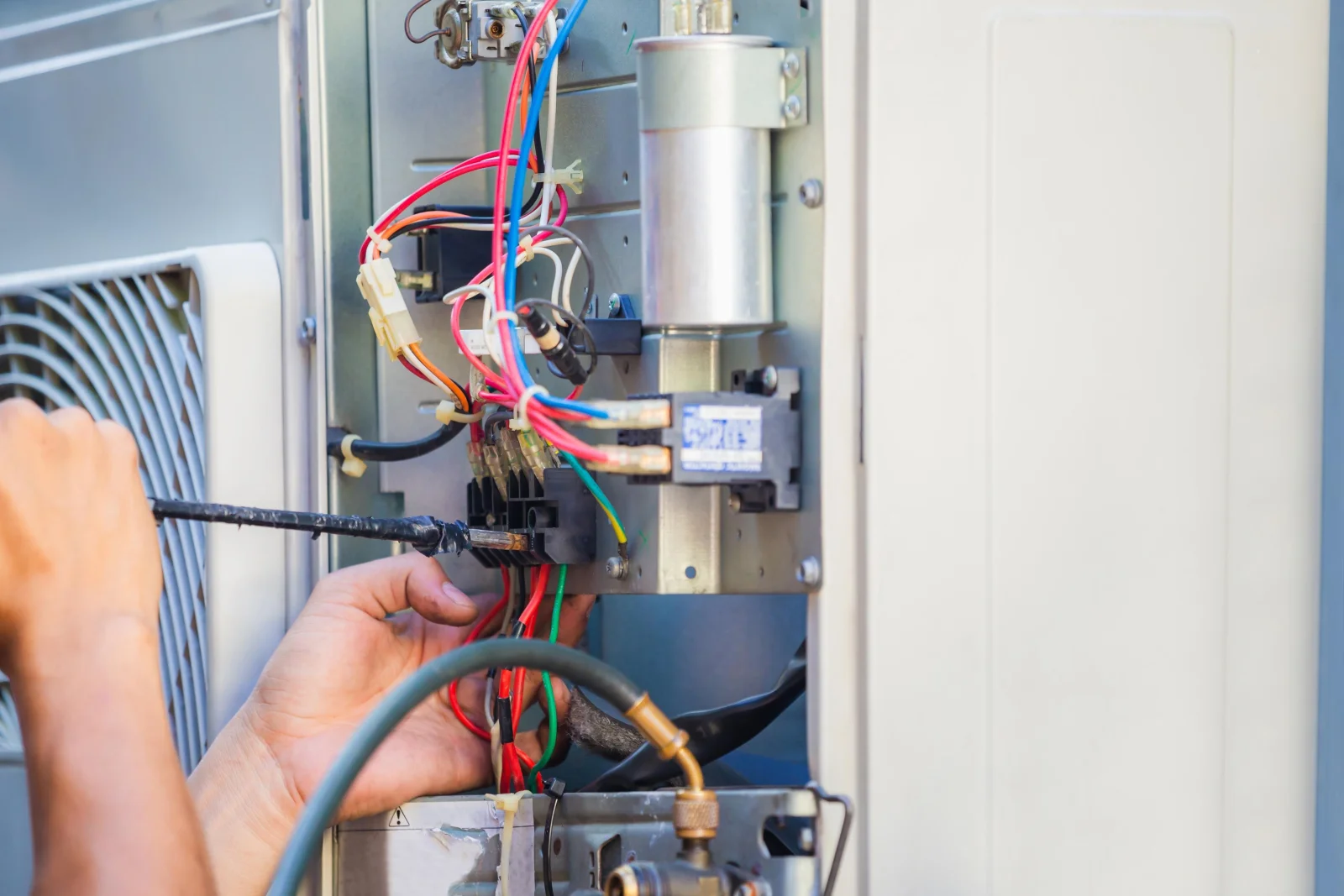 Close-up of a technician's hands working on a worn furnace control board and wiring during a replacement inspection.