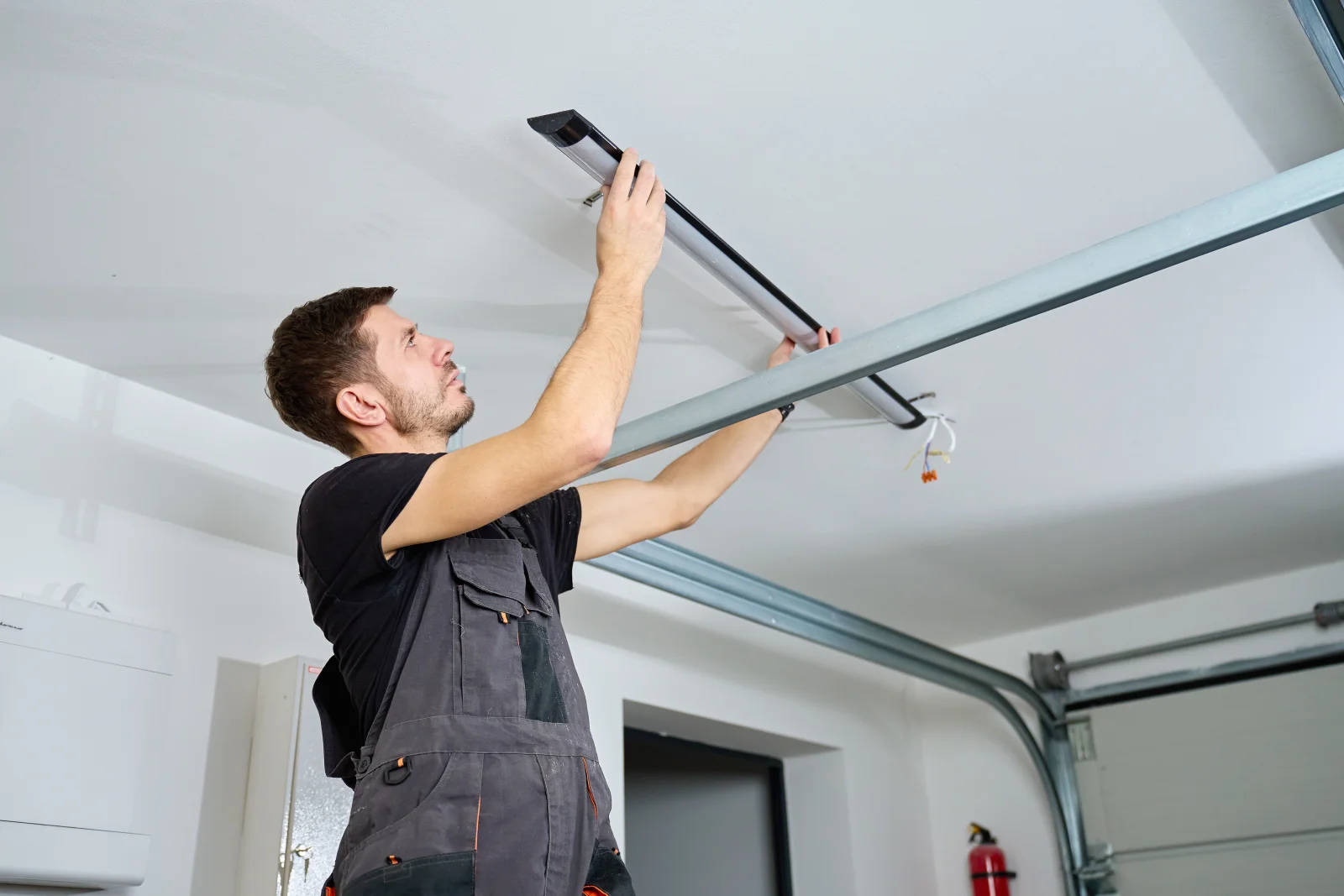 A technician on a ladder installing overhead garage door track and hardware in a Phoenix, Arizona garage.