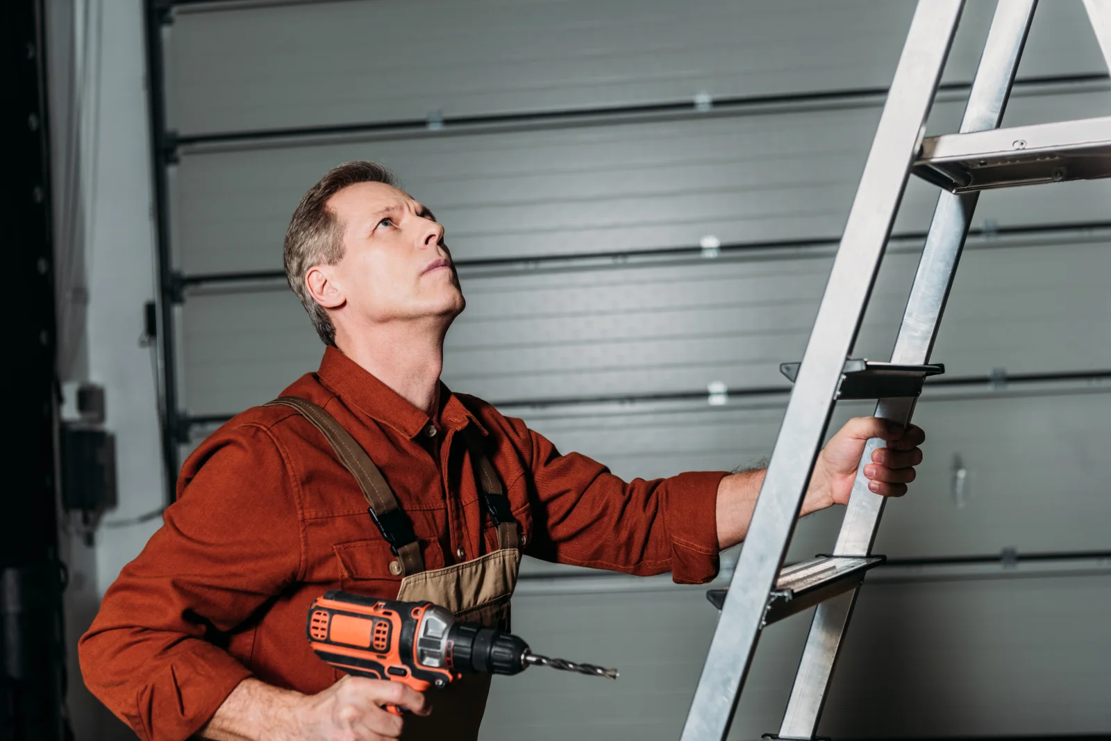 A stretched extension spring along the upper track of a residential garage door in Phoenix, Arizona, the older-style spring system a technician checks alongside torsion springs.