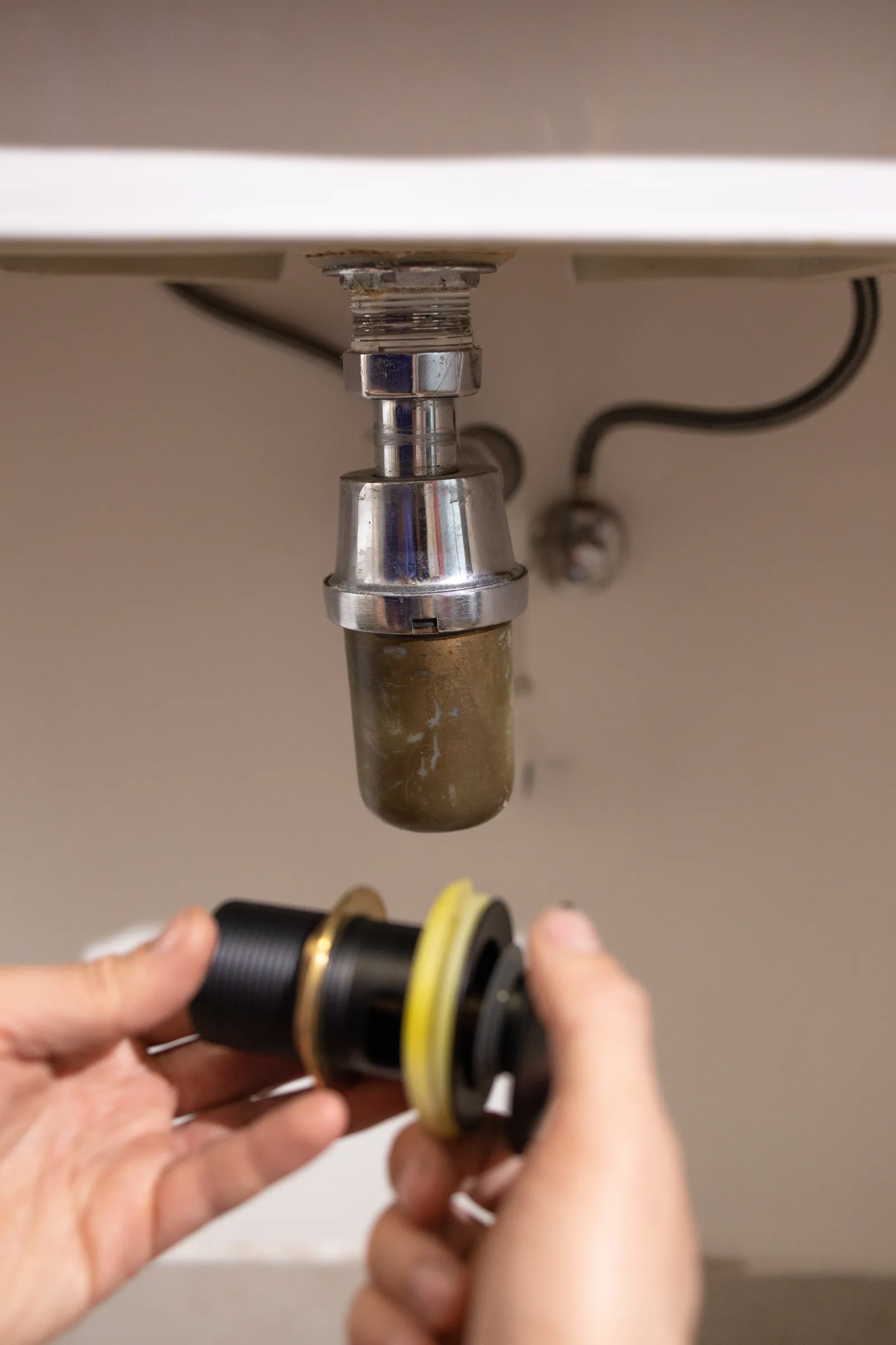 garbage-disposal-repair-phoenix-under-sink-work A plumber's hands repairing a garbage disposal mounted under a kitchen sink, the kind of under-sink work a vetted Phoenix pro handles when a disposal jams, hums, or leaks.