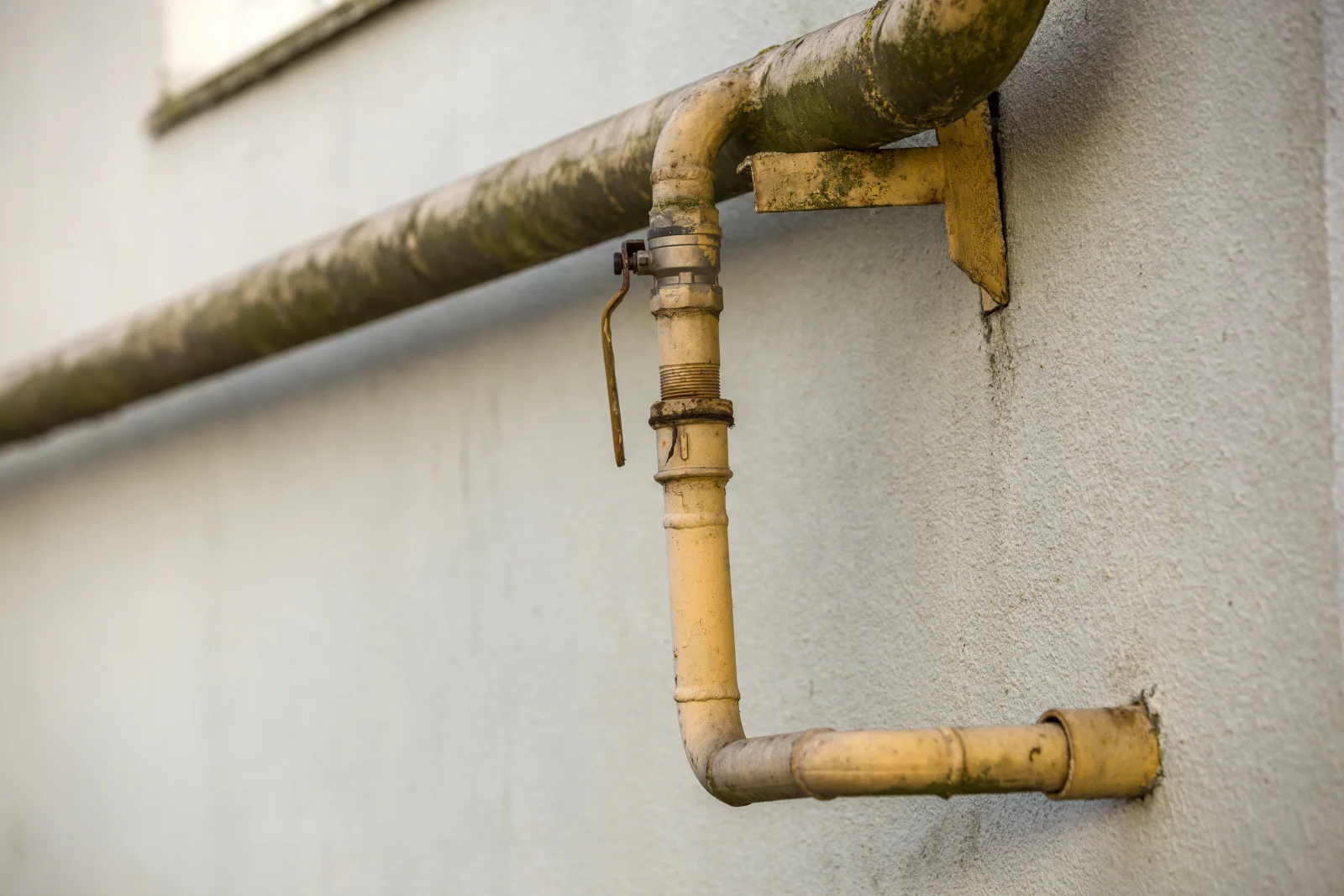 Gas line repair in Phoenix, Arizona — a yellow gas shutoff valve and line fitting mounted on a home's exterior wall.