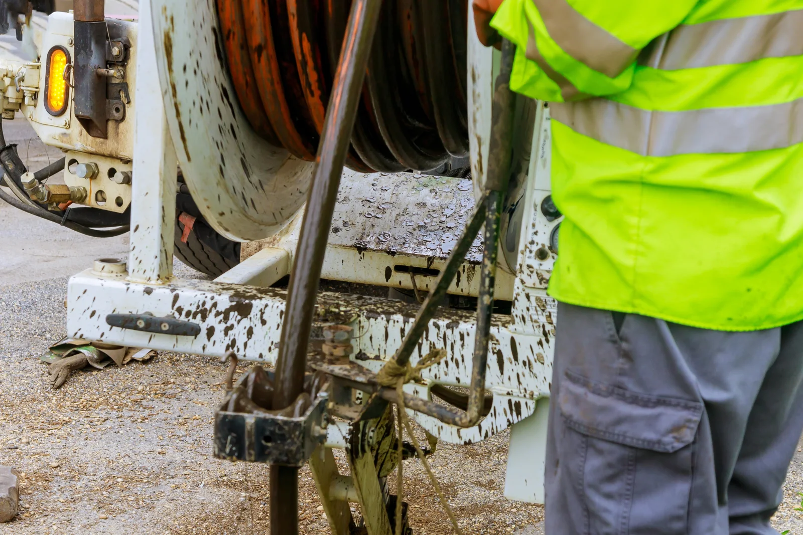 grease-trap-cleaning-phoenix-vacuum-truck-pump-out-service Grease trap cleaning in Phoenix, Arizona — a technician in a high-visibility vest operating a vacuum hose reel during an exterior grease interceptor pump-out.