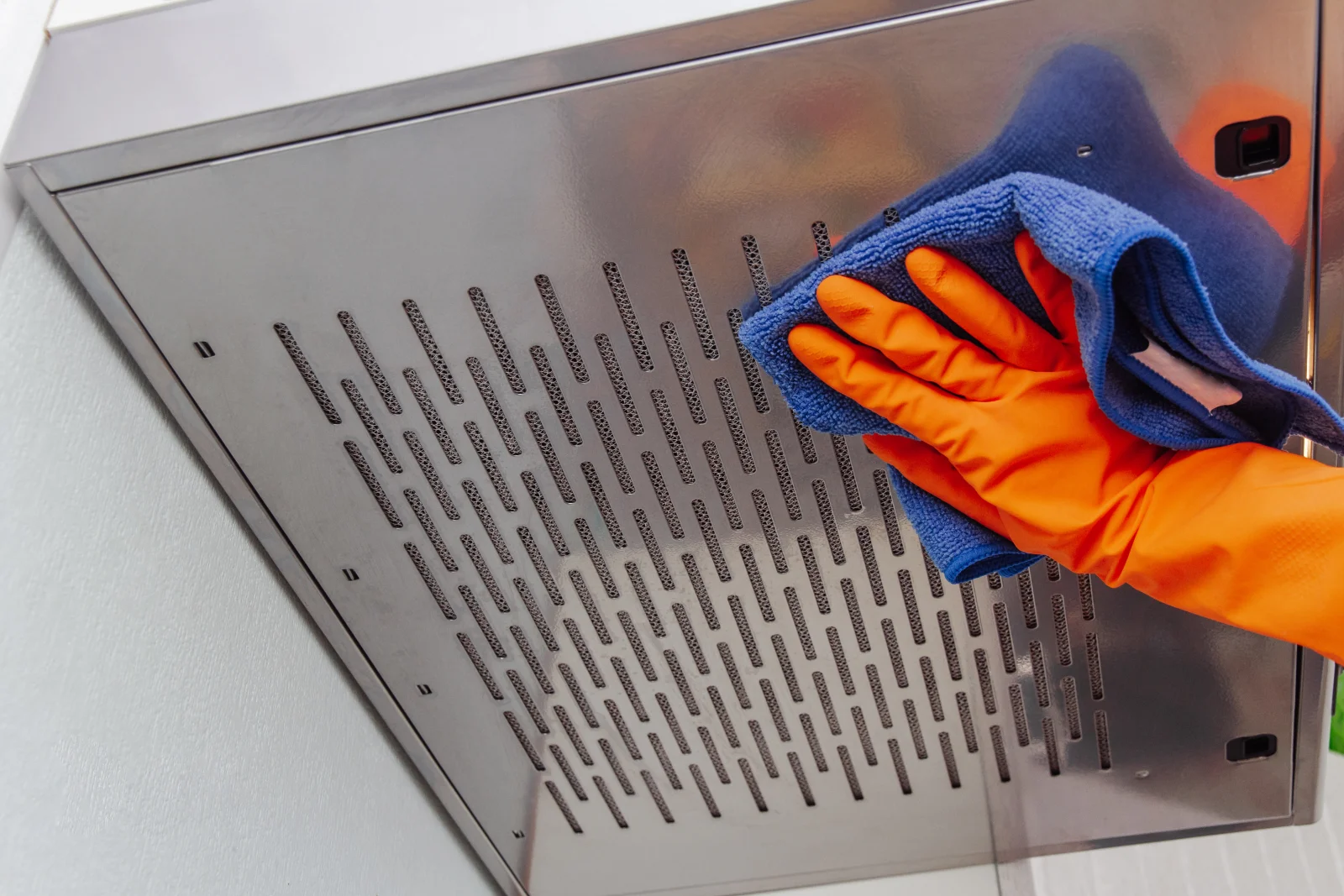 A gloved technician wiping down a bare-metal stainless steel exhaust hood filter during a Phoenix hood cleaning, the degreased finish a fire marshal and insurer expect to see documented.