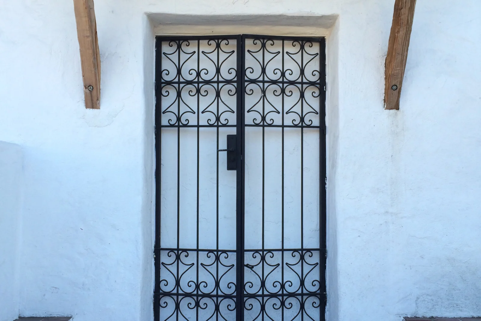 house-lockout-phoenix-front-door A wrought-iron security gate set into the white stucco entryway of a Phoenix home, the kind of front door residents get locked out of in the desert heat.