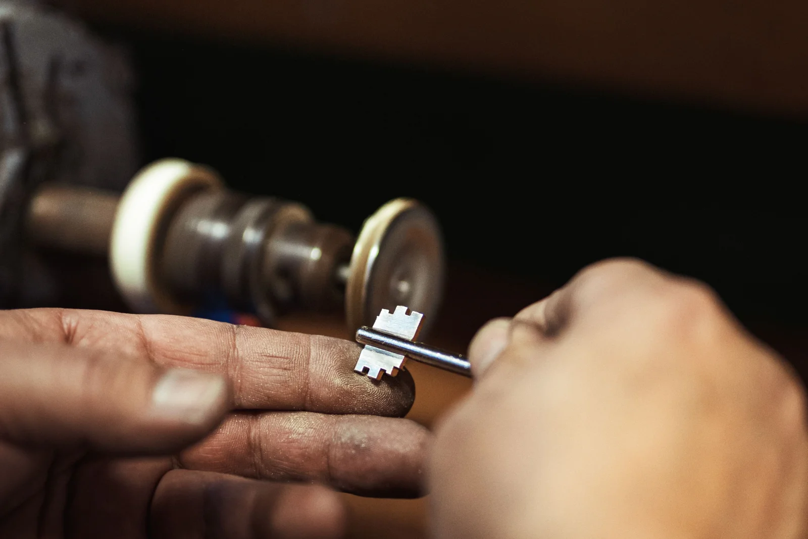 house-lockout-phoenix-rekey-deadbolt A Phoenix locksmith rekeying a home's deadbolt cylinder at a workbench after a house lockout, cutting a new key so old keys no longer work on the door.