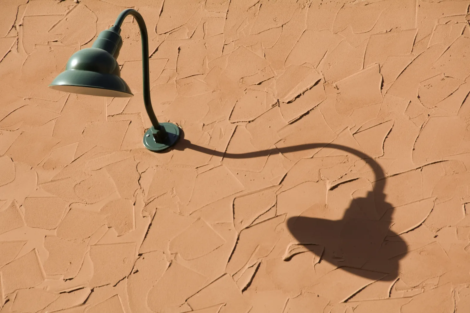 A sun-faded outdoor light fixture on a Phoenix home showing the heat and UV damage that leads to flickering and failure.