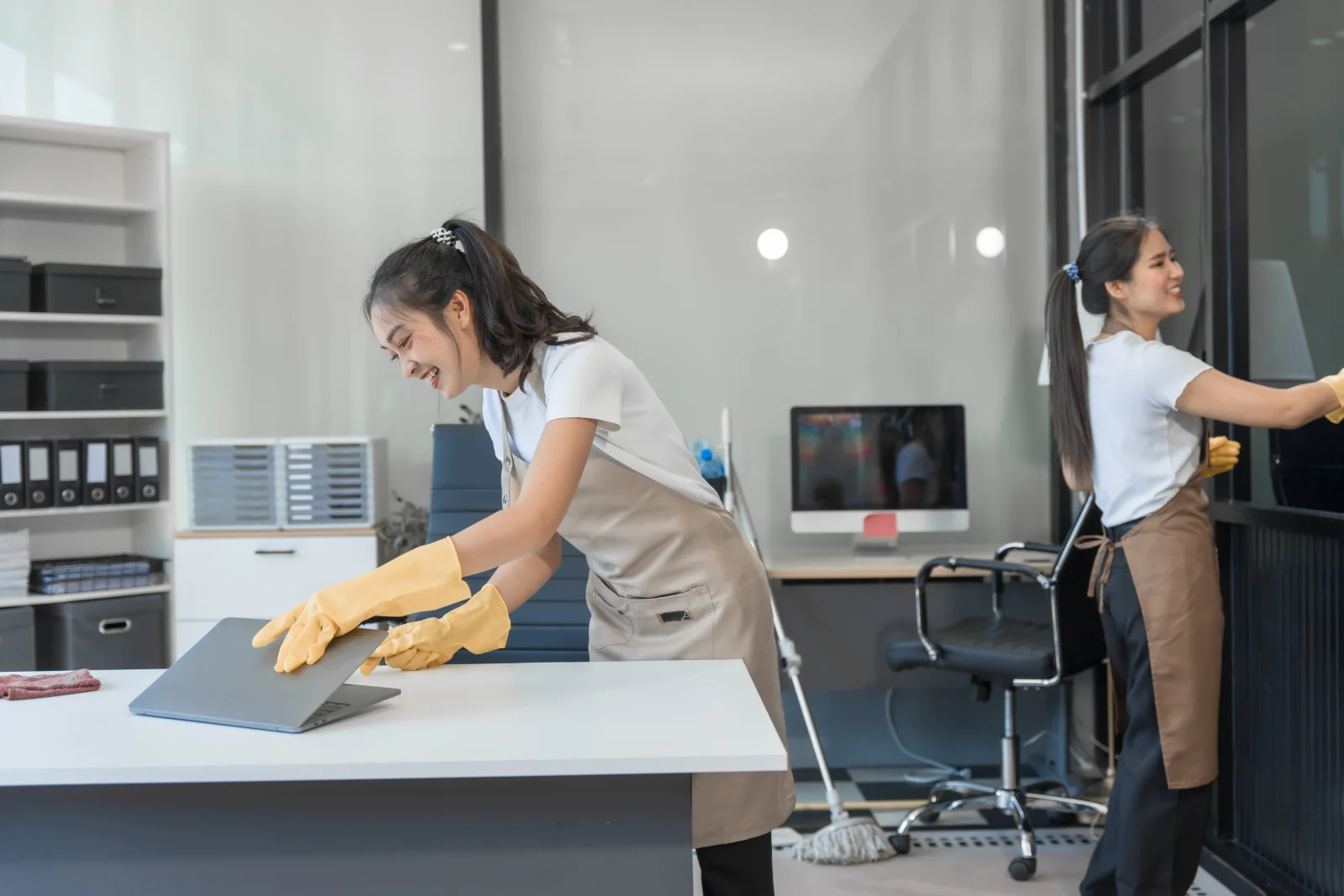 office-cleaning-services-phoenix-az-cleaner-wiping-desk-workstation Office cleaning services in Phoenix, AZ — a cleaner in professional uniform wiping down a desk workstation in a modern office.