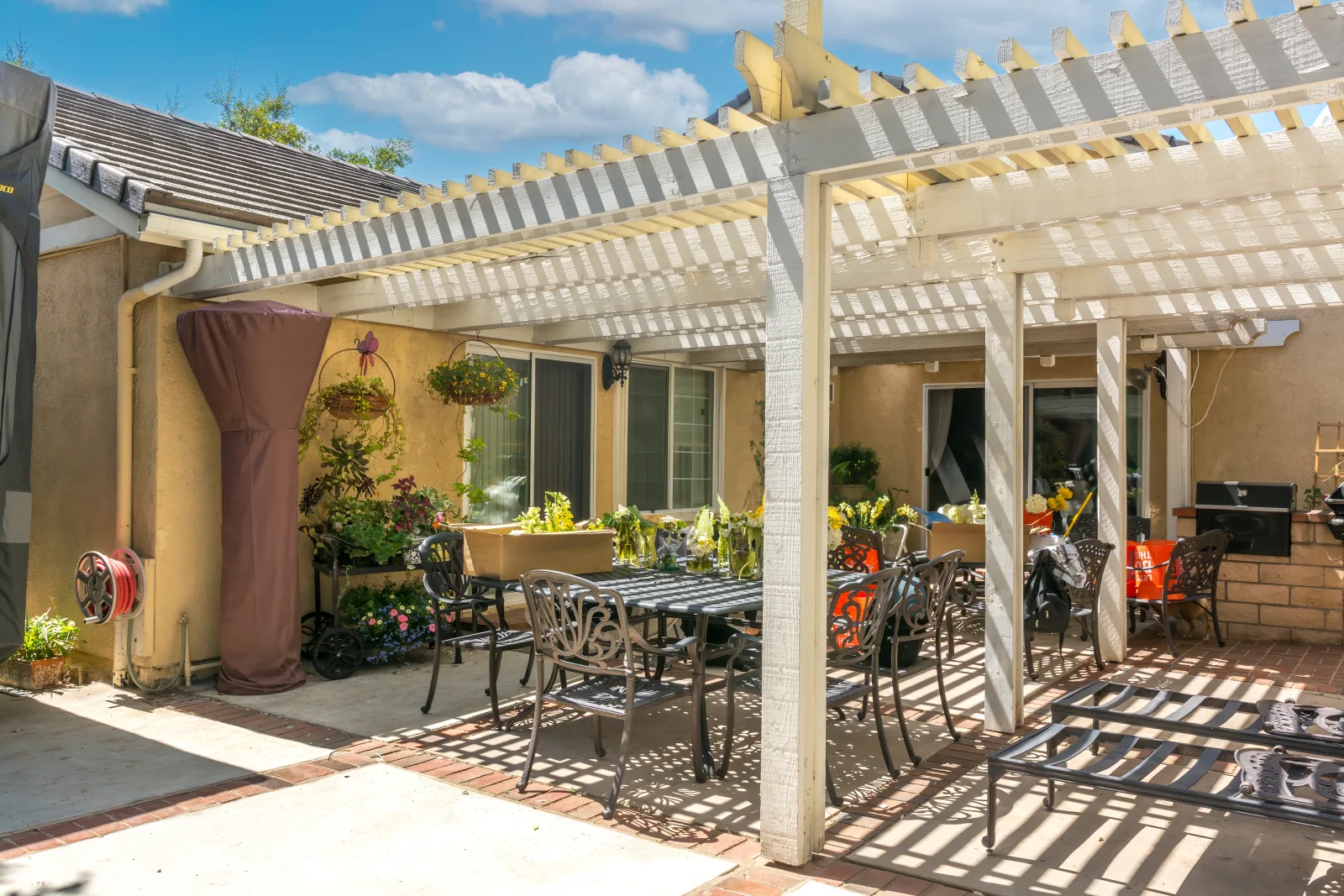 patio-builders-phoenix-az-finished-covered-patio A finished covered patio in Phoenix, Arizona with an alumawood pergola, dining seating, and a stucco home exterior, an example of a completed outdoor-living build.